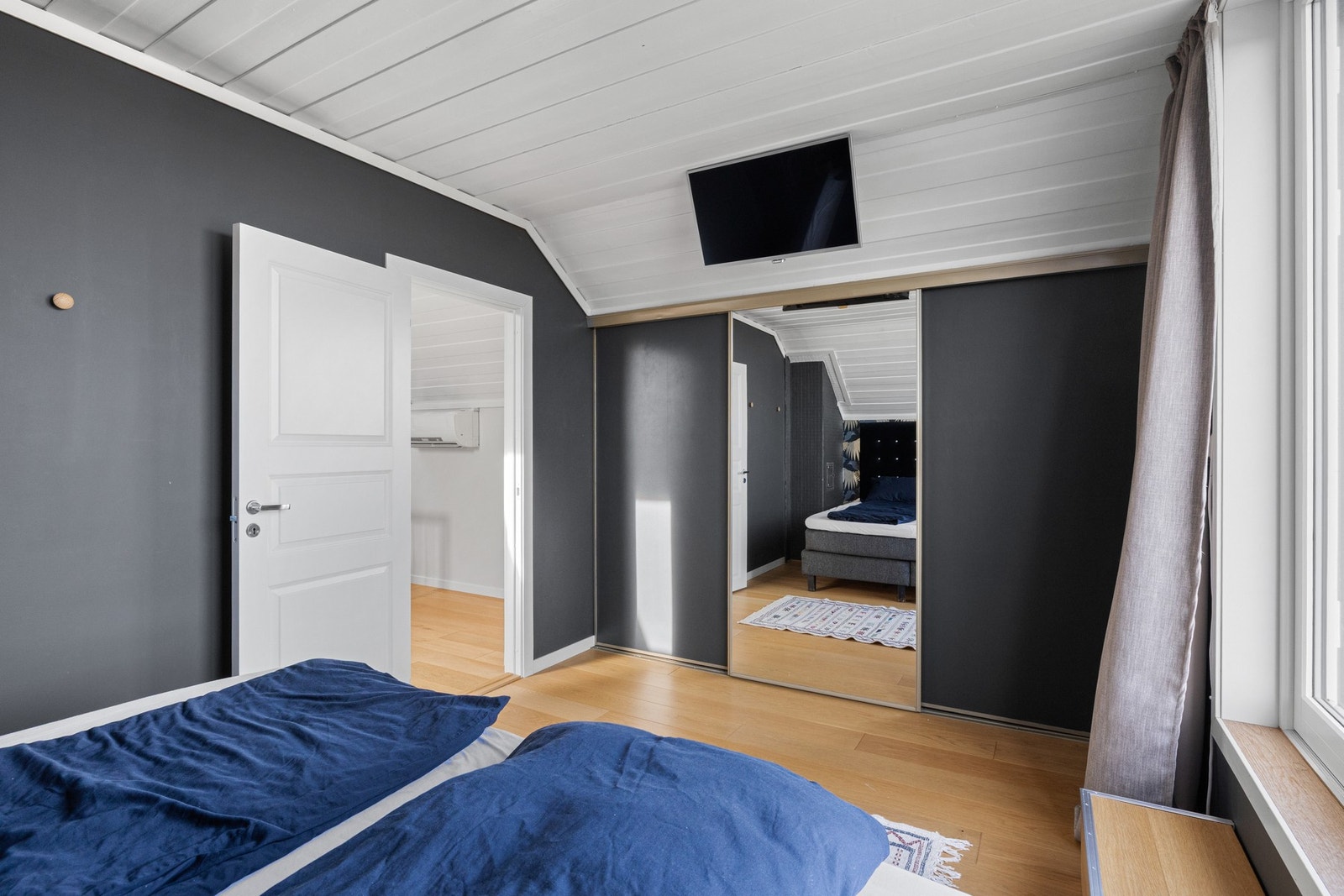 Langs den ene veggen har rommet en plassbygd skyvedørsgarderobe med dels speilfronter. Galleribilde