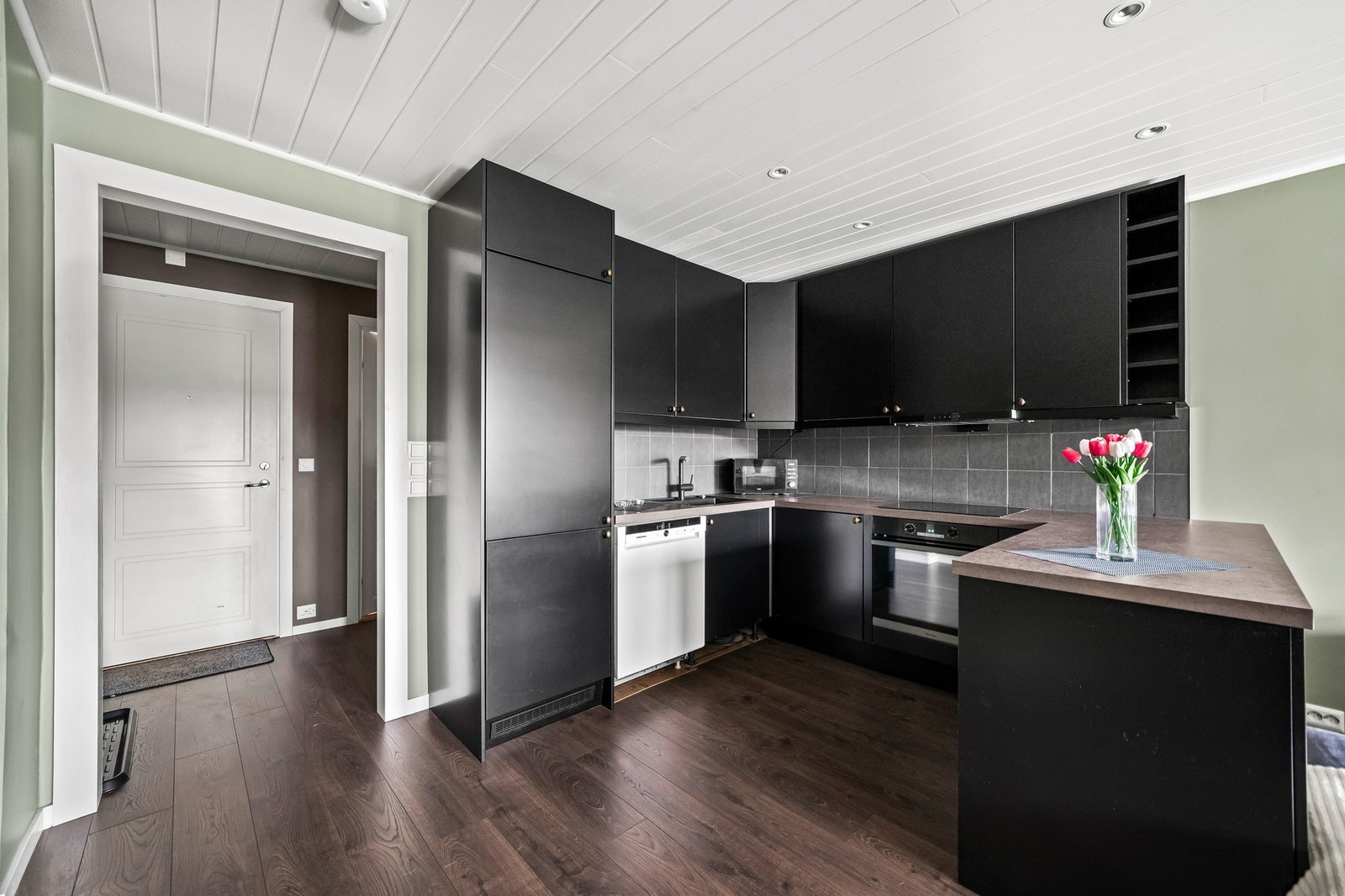 Integrert platetopp og kjøleskap. Kjøkkenet har godt med skap - og benkeplas. Galleribilde