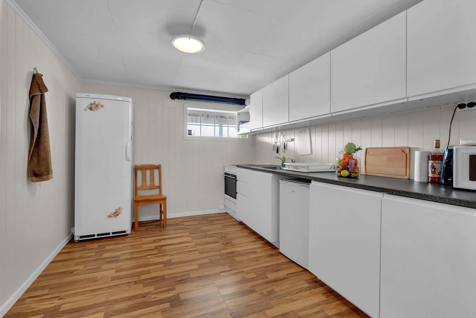 Lyst og innbydende kjøkken i kjeller med slette fronter og rikelig med skap og benkeplass. Galleribilde