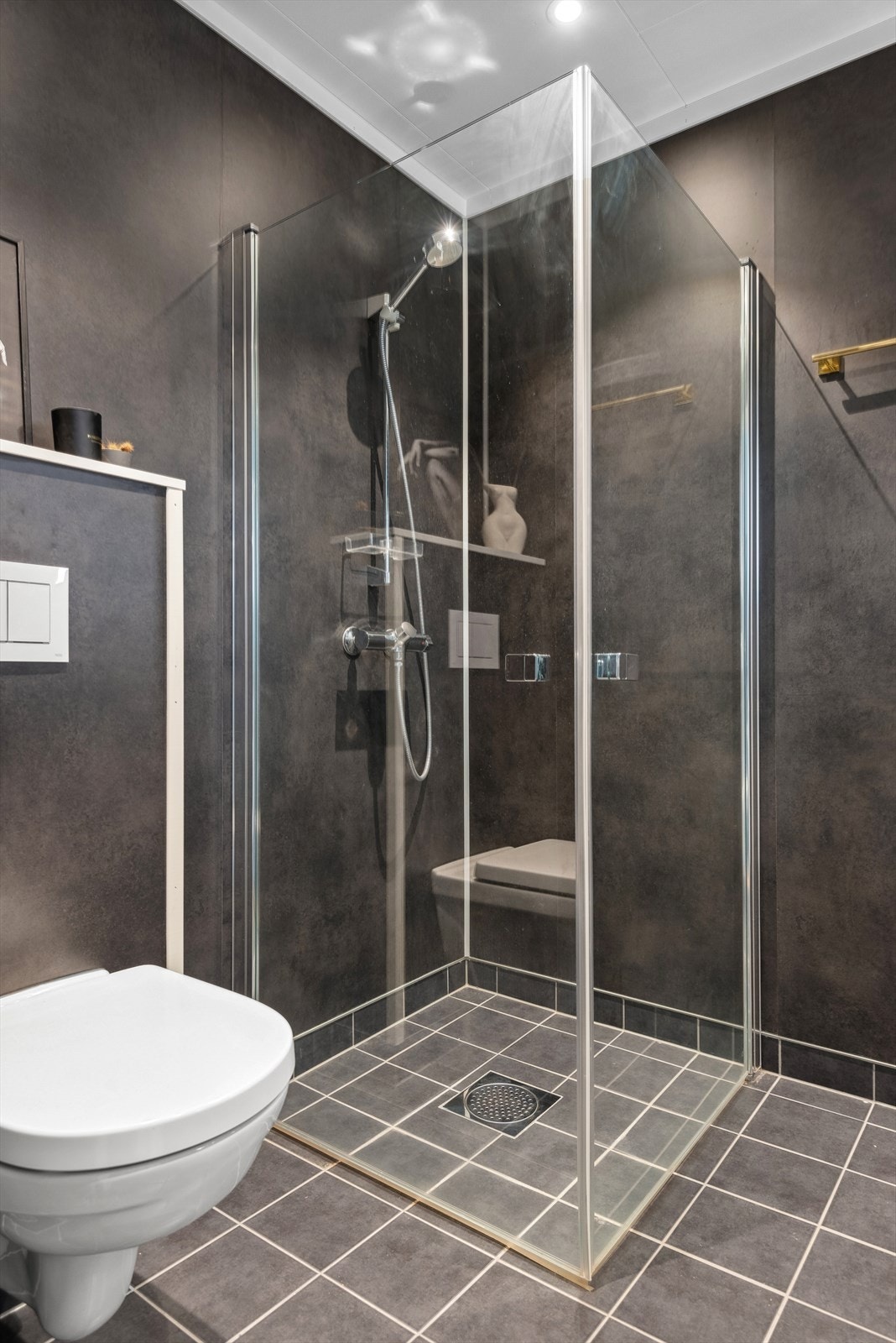 Badet har dusjsone med glassdører og veggehengt wc. Galleribilde