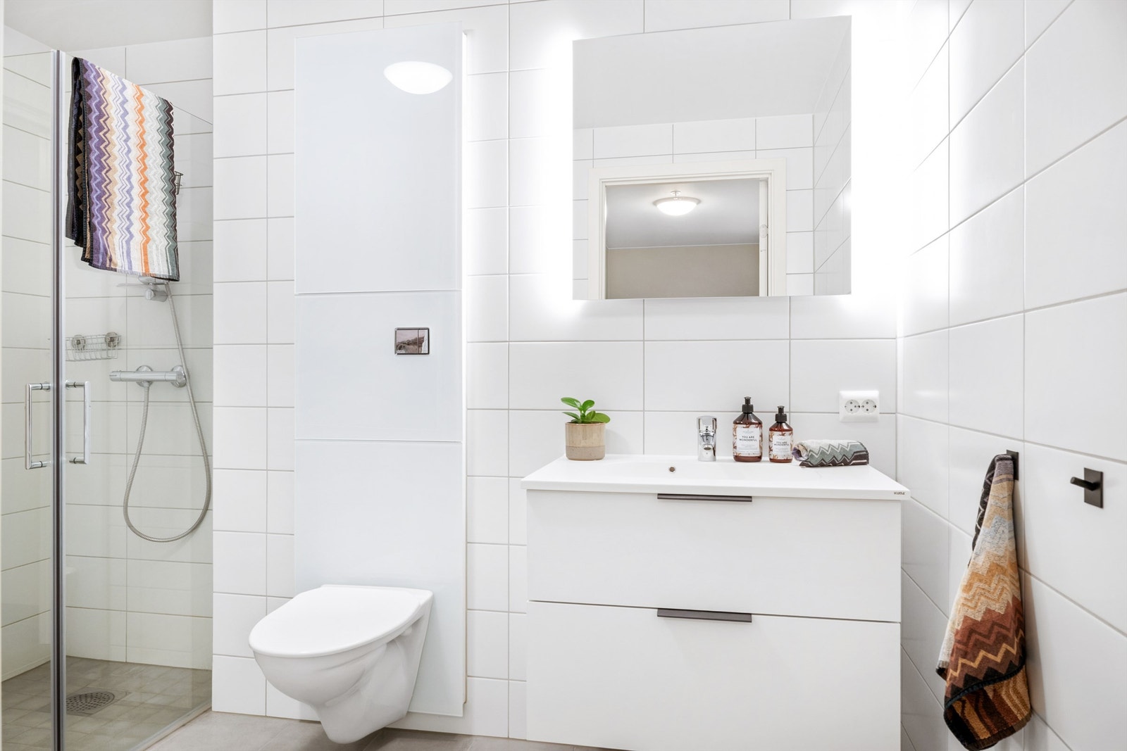 Badet er helfliset, med vegghengt wc, innredning med helstøpt servant, speil med innebygget belysning og dusjløsning. Det er varmekabler i gulvet. Galleribilde