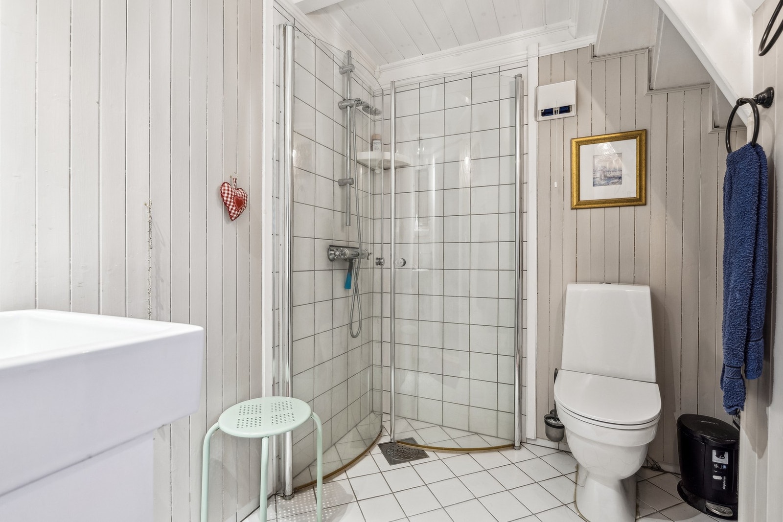 Bad med varmekabler i gulv. Rommet er utstyrt med baderomsinnredning med servant, gulvstående toalett
og dusjhjørne med glassdører Galleribilde