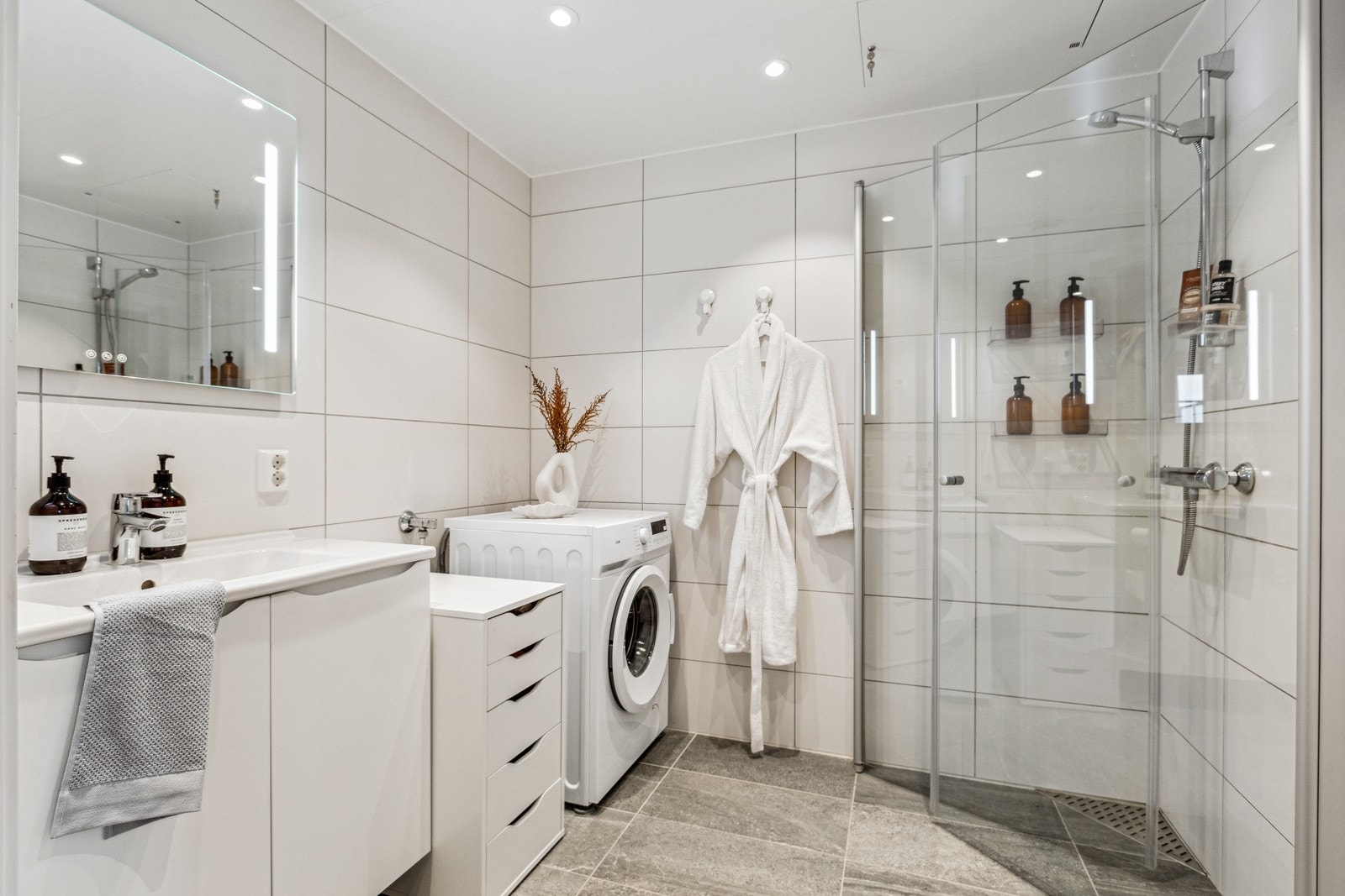 Lekkert baderom med store fliser og dusjhjørne med glassdører. Galleribilde