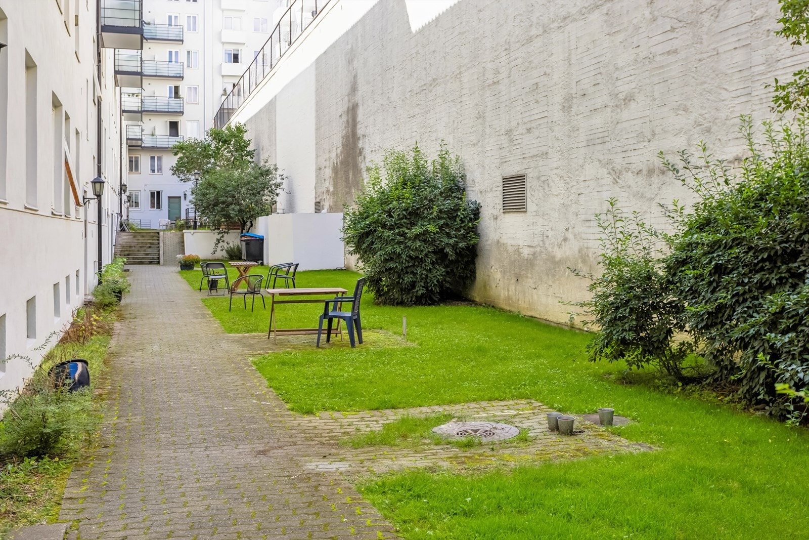 Skjermet felles bakgård med beplantning, sitteplasser og grillmuligheter. Flotte utearealer med stensatte gangveier og opparbeidet plen i forkant av bygården som ligger noe tilbaketrukket fra gaten. Galleribilde