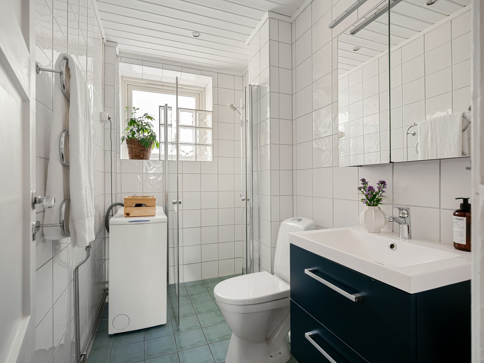 Badet er innredet med dusjhjørne, servant med skuffer, speilskap og toalett. Det er både plass og opplegg til vaskemaskin her inne. Galleribilde