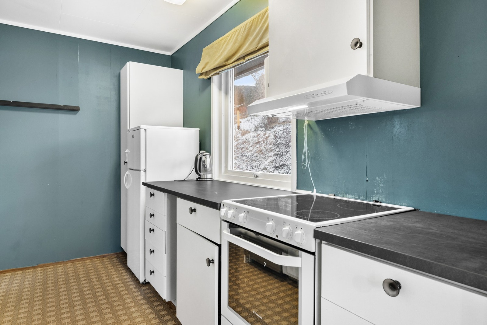 Kjøkkenet har innredning med malte glatte fronter, benkeplaten er av laminat. Galleribilde