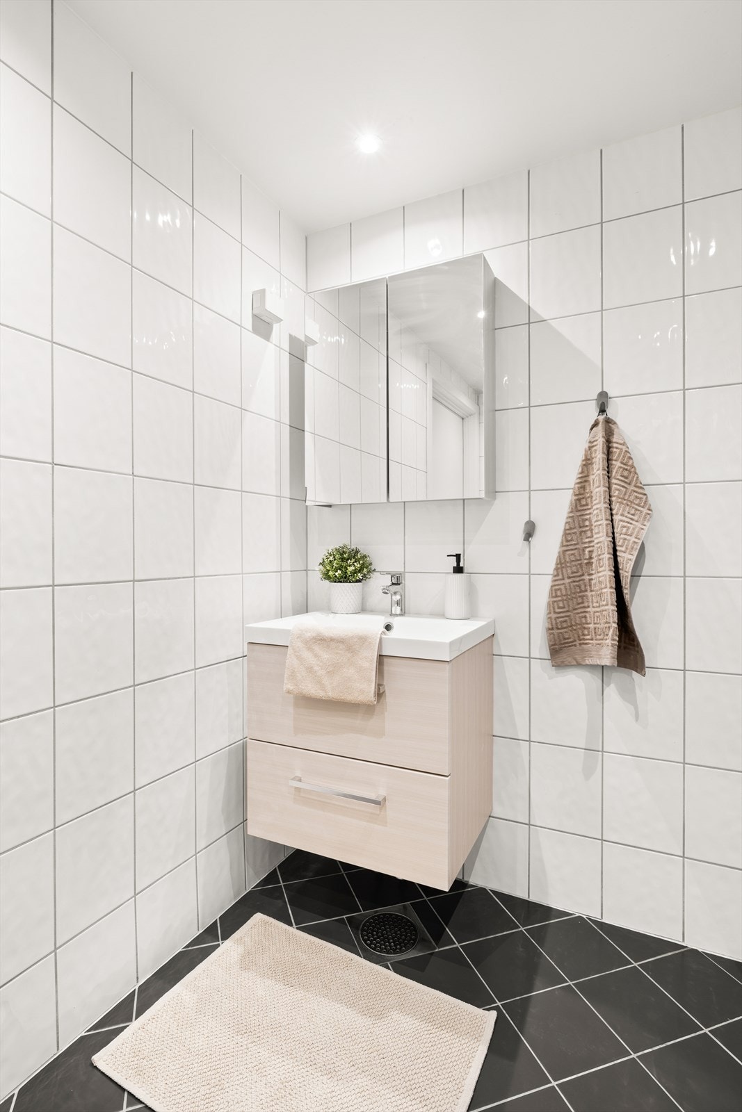 Badet har servant og speilskap med innredning, opplegg for vaskemaskin, toalett og dusjhjørne. Galleribilde