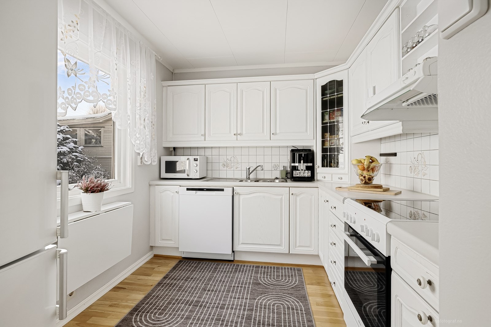 Kjøkkenet har innredning med hvite, profilerte fronter og benkeplaten er av laminat Galleribilde