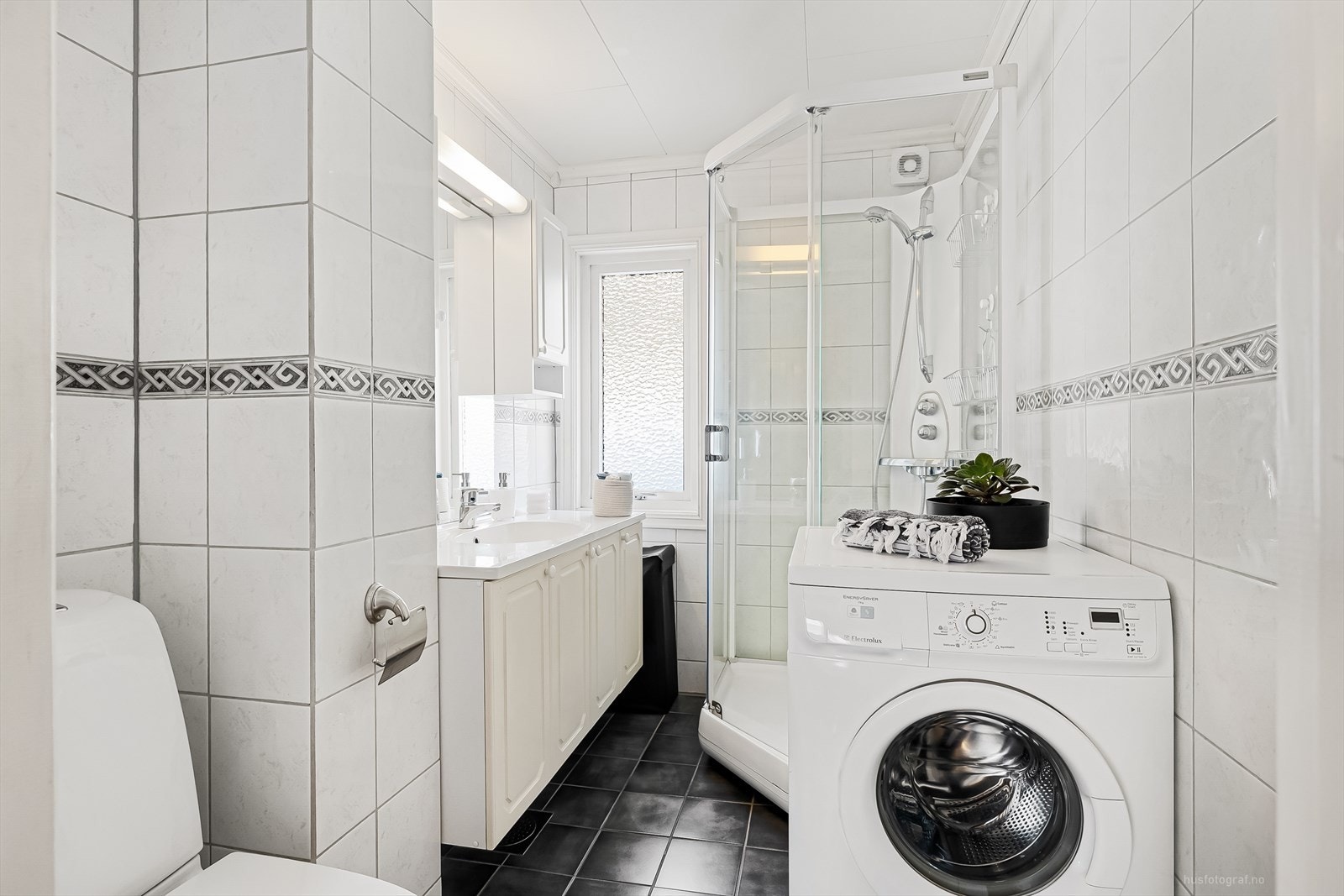 Flislagt bad innredet med nedfelt servant, toalett (nytt i 2022), dusjkabinett og opplegg for vaskemaskin Galleribilde