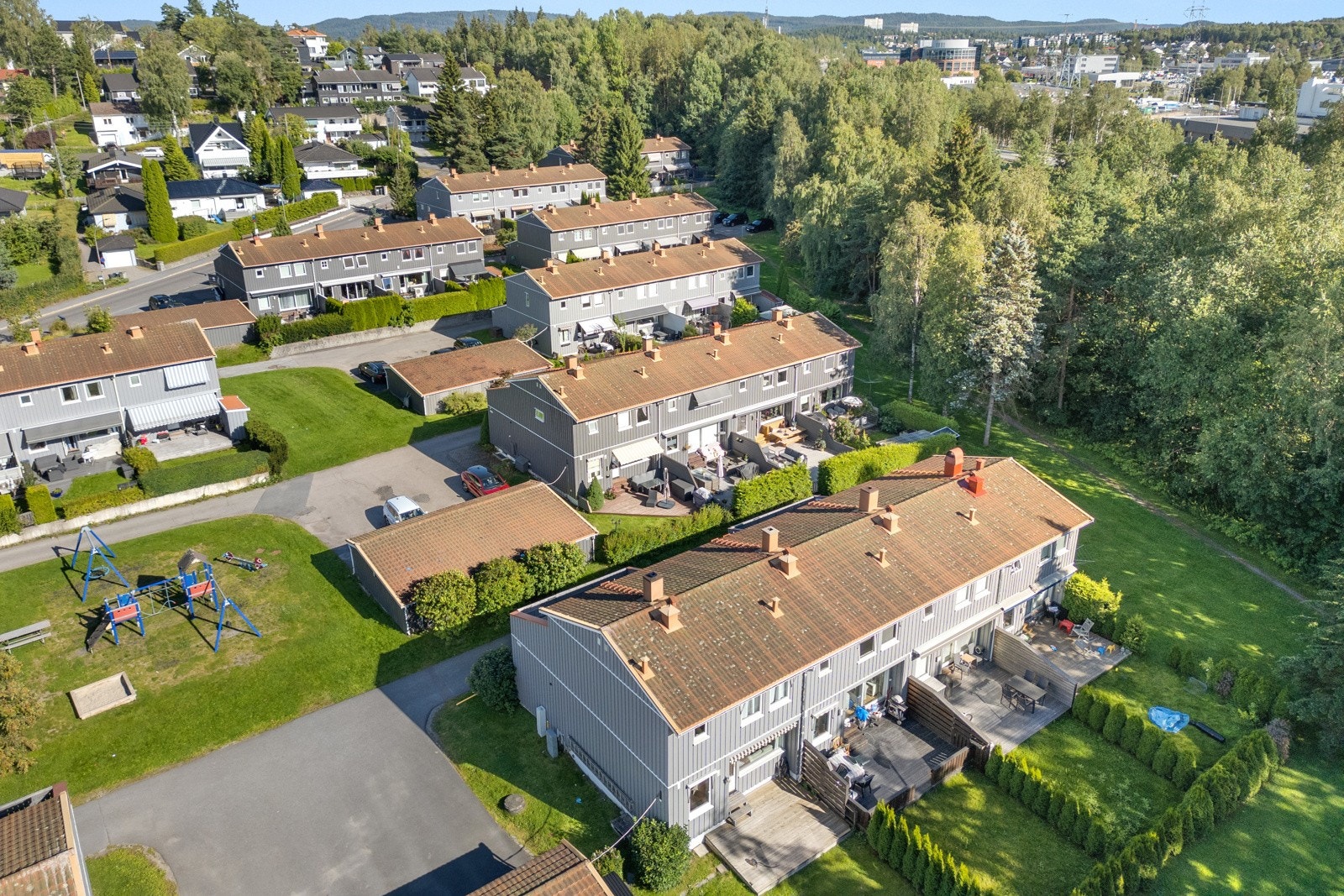 Rekkehuset ligger i et familievennlig nabolag omgitt av skogholt og frodige grøntarealer rundt byggene. Galleribilde