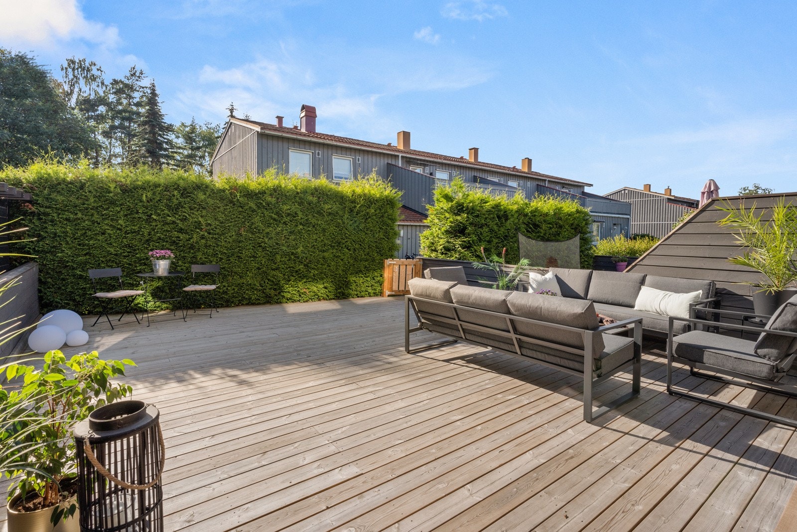 Terrassen har dekke av terrassebord, skjermende markise, levegger på sidene og en tettvokst, vintergrønn hekk i enden, som gjør det hele til en skjermet oase. Galleribilde