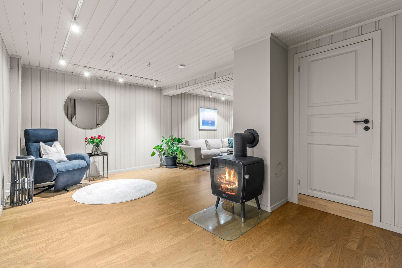En peisovn, lik som i hovedstuen, gir rommet ekstra hygge. Det er montert flere spotskinner i taket for belysning. Galleribilde