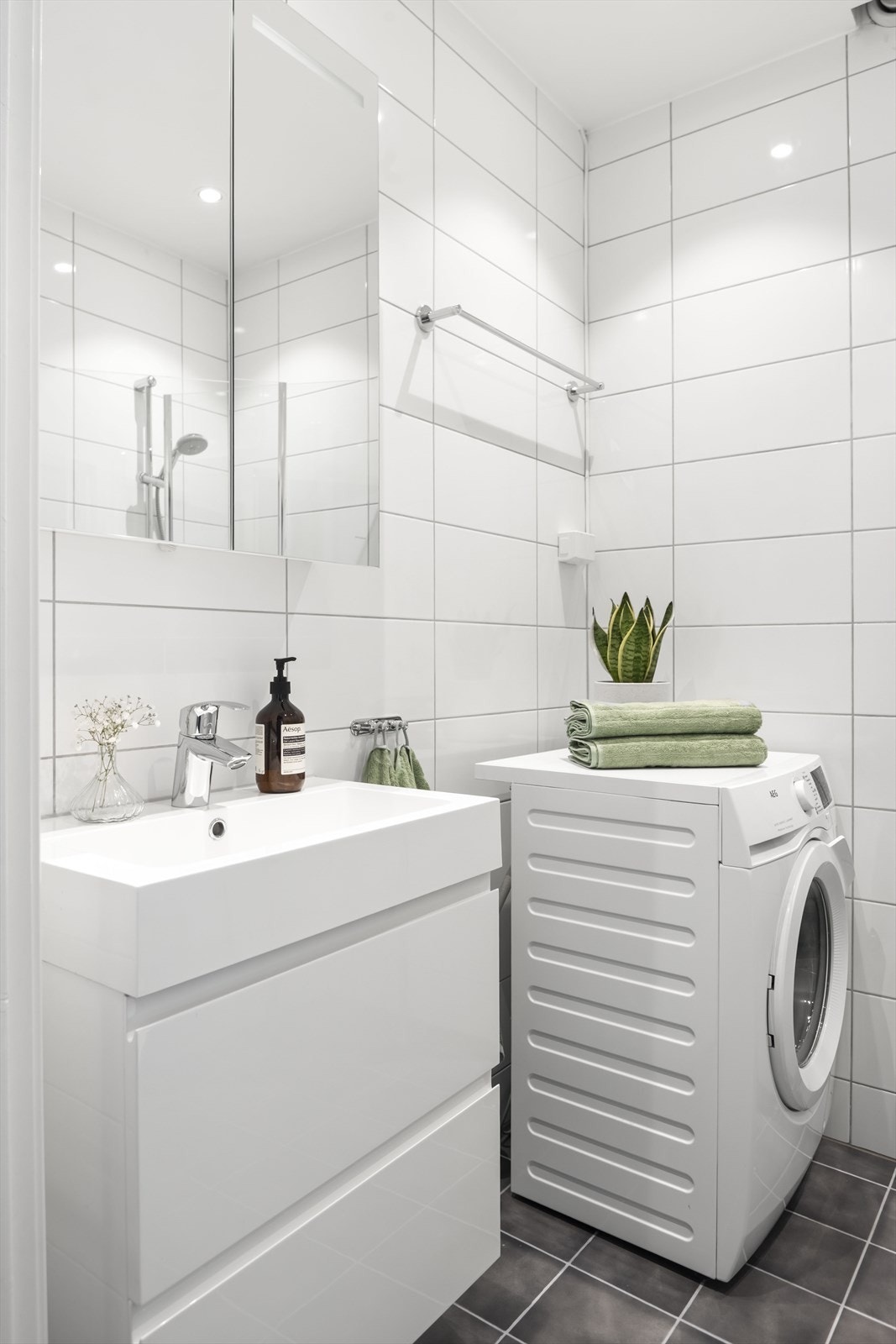 Stilren innredning med heldekkende servant over innredning, speilskap med belysning og vegghengt toalett. Det er opplegg for vaskemaskin. Galleribilde