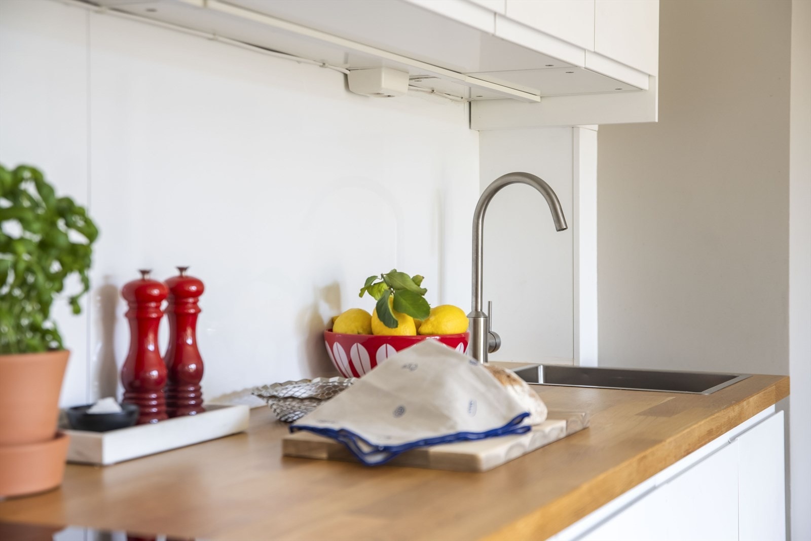 Videre er kjøkkenet utstyrt med arbeidslys over heltre benkeplate, vaskekum og ventilator. Galleribilde