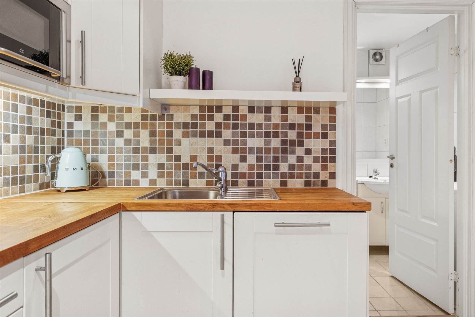 Downlights i himling sørger for godt og behagelig lys. Kjøkkenet er holdt i tidsriktig material og fargevalg og har flis over benkeplate som gjør det enkelt og rengjøre Galleribilde