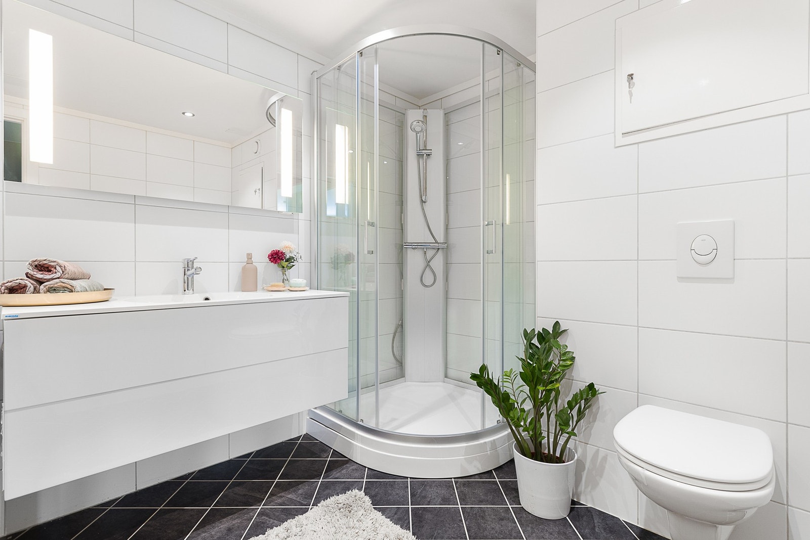 Badet er innredet med dusjkabinett, toalett, baderomsinnredning med servant og opplegg for vaskemaskin. Det er også fellesvaskeri til gratis benyttelse i kjeller. Galleribilde