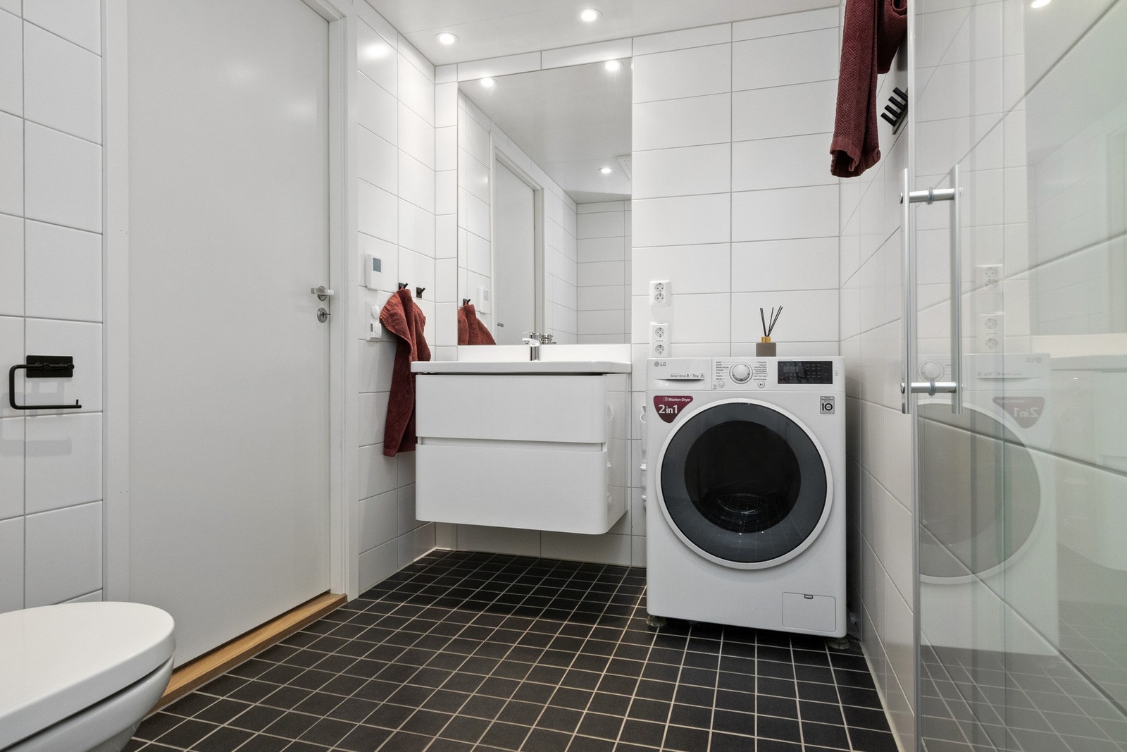 Leiligheten har to delikate bad i hver sin etasje. Badene er stilrent innredet med hvite veggfliser og sorte mosaikkfliser på gulvet. Galleribilde