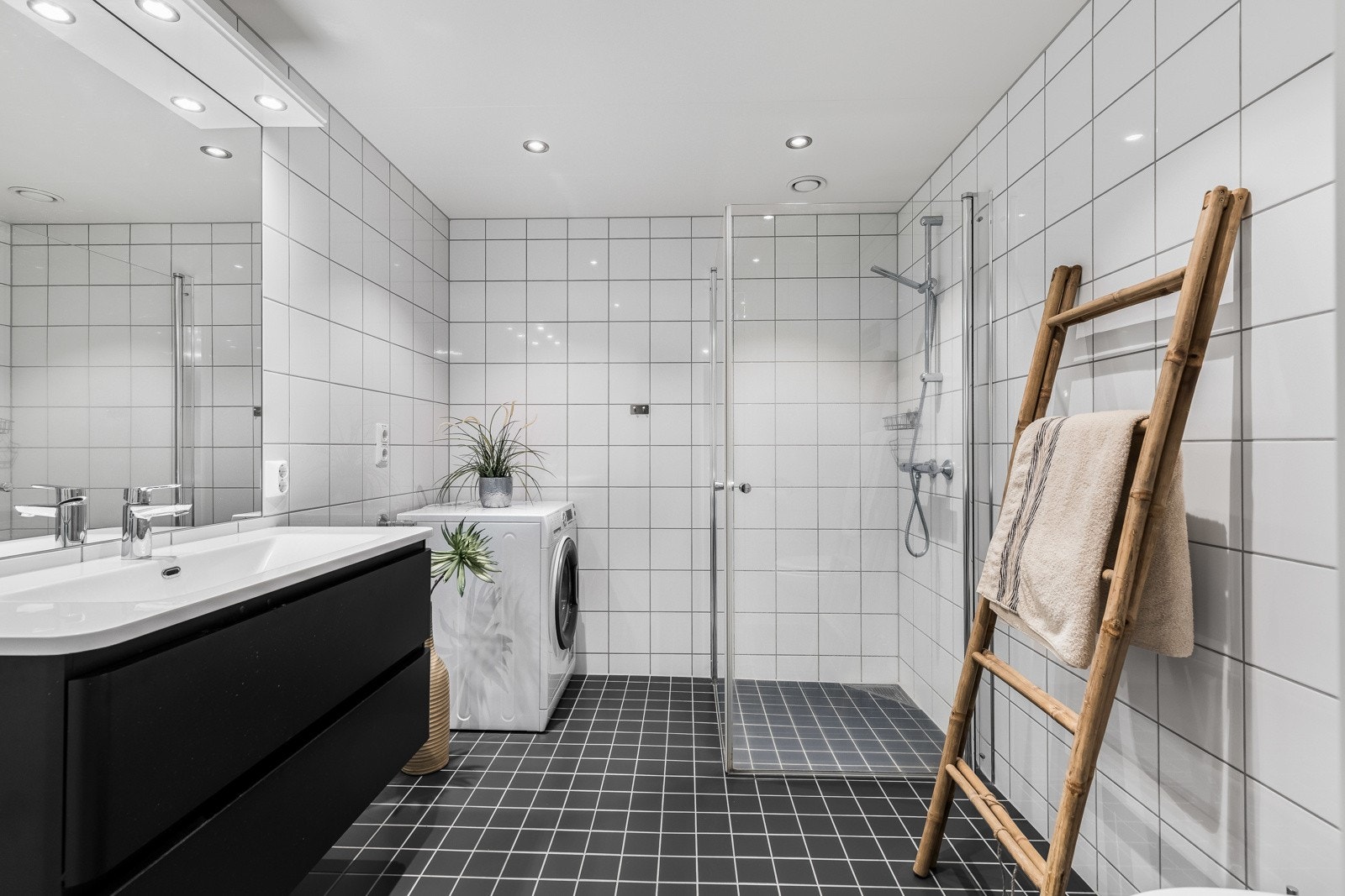 Badet fremstår som moderne, velholdt og delikat, med hvite fliser på veggene, downlights i himlingen og koksgrå fliser på gulv med elektrisk gulvvarme. Galleribilde