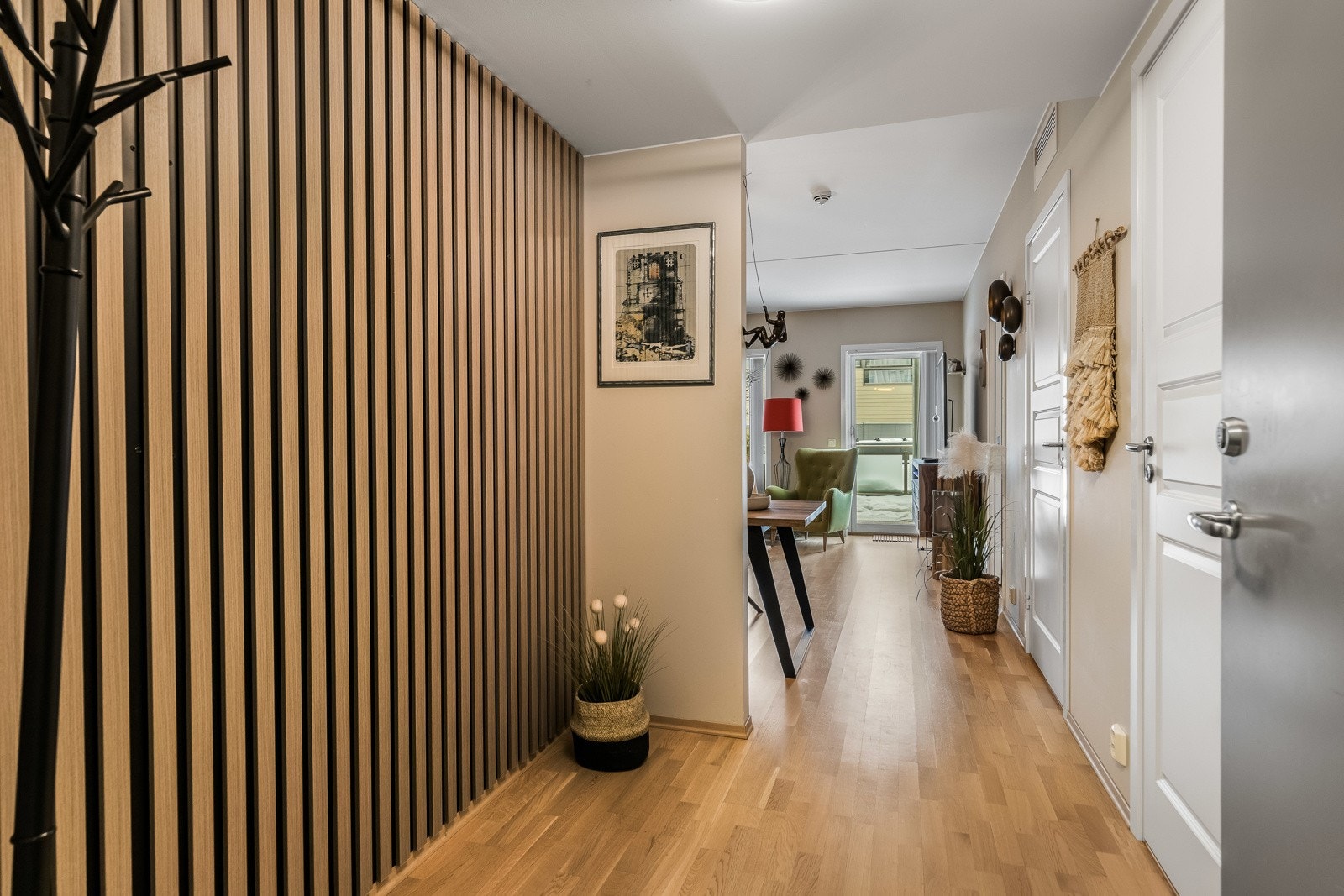 Entreen har én vegg dekket med tidsmessige eikespiler, og resten av veggene er malt i en fin beigetone som fremhever parkettgulvet. Galleribilde