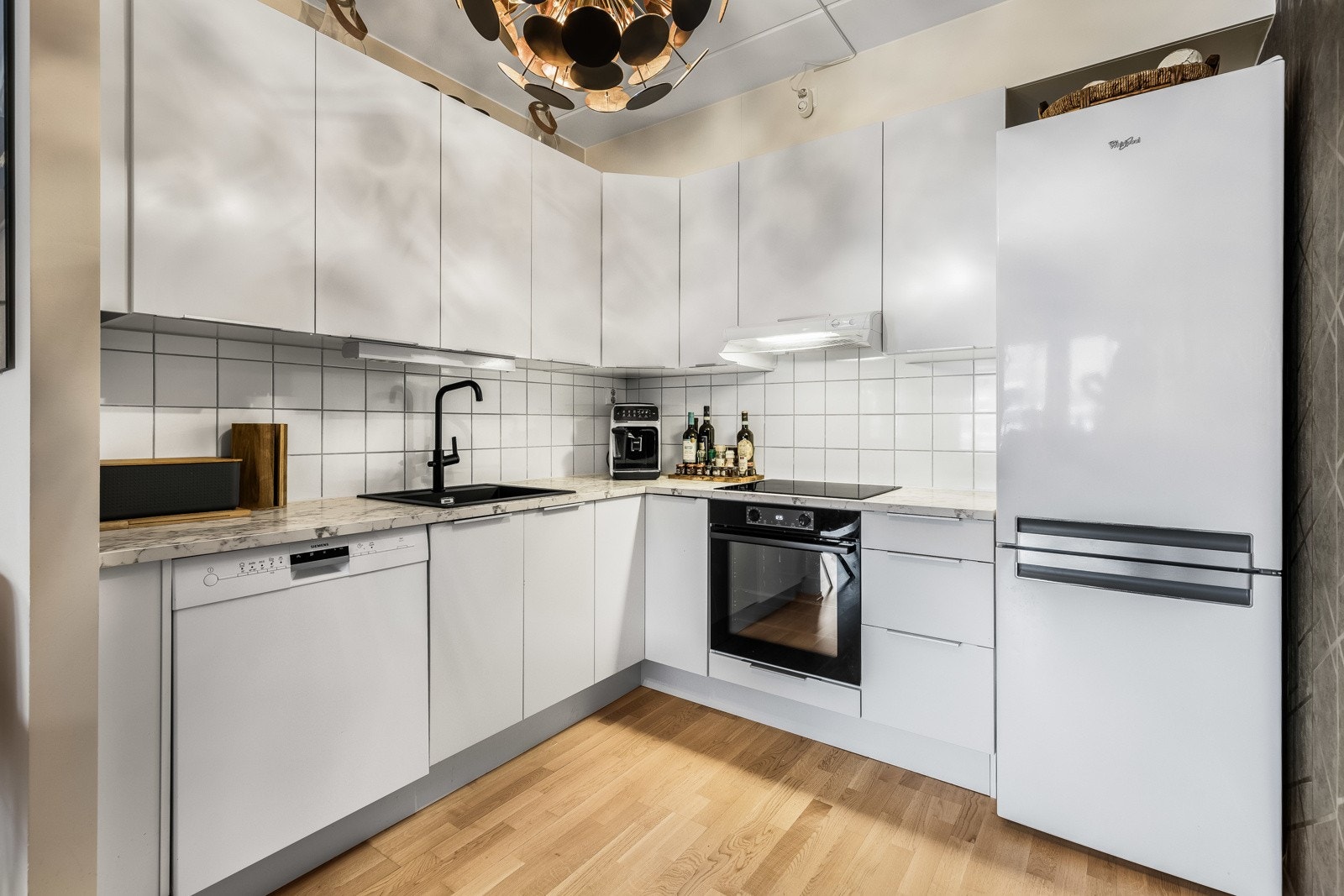 Veggene over benken er kledd med hvite fliser, og under overskapene er det montert god arbeidsbelysning. Galleribilde