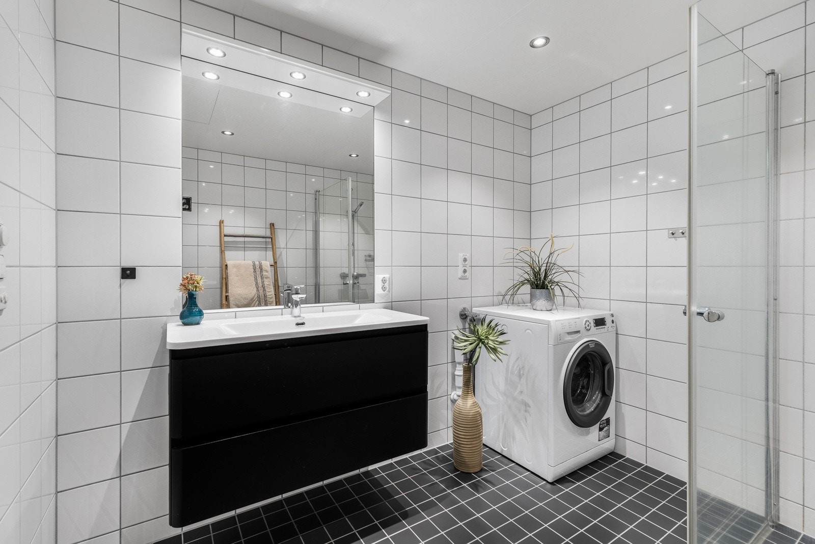 Baderomsinnredningen har sorte fronter og består av en heldekkende servant på en skuffeseksjon og et stort speil med belysning. Galleribilde