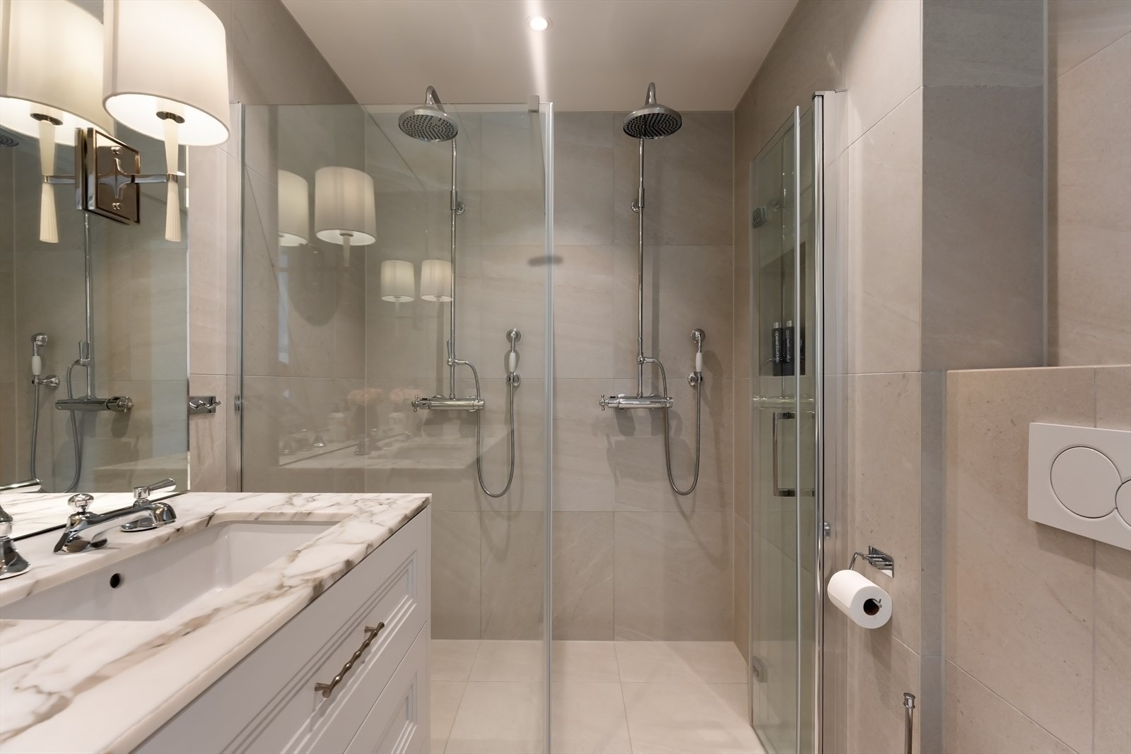 Badet har dobbel dusj, plassbygget benkeskap med profilerte fronter og Arabescato marmor benkeplate Galleribilde