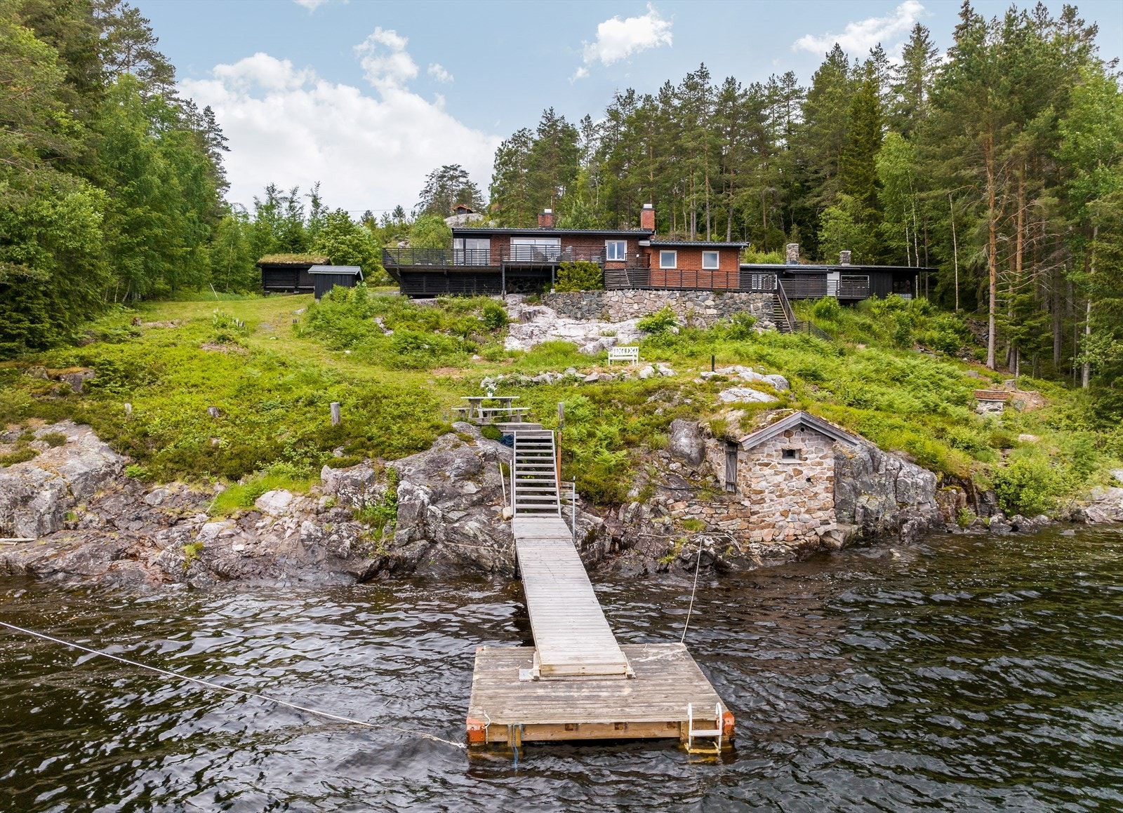 Tomten er flott opparbeidet med plenarealer, beplantning samt naturtomt i skrånende fjellterreng. Det er murer i terrenget, fint forblendet med naturstein. Kort vei ned til vannet (ca. 65m strandlinje) hvor det er en flytebrygge, samt en liten sandstrand. Galleribilde