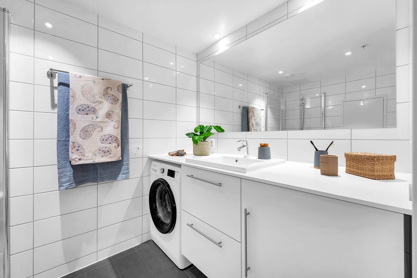 Badet er innredet med vegghengt klosett, servant nedfelt i innredning og dusjhjørne med svingbare glassdører. Det er opplegg for vaskemaskin og badet har balansert ventilasjon. Galleribilde