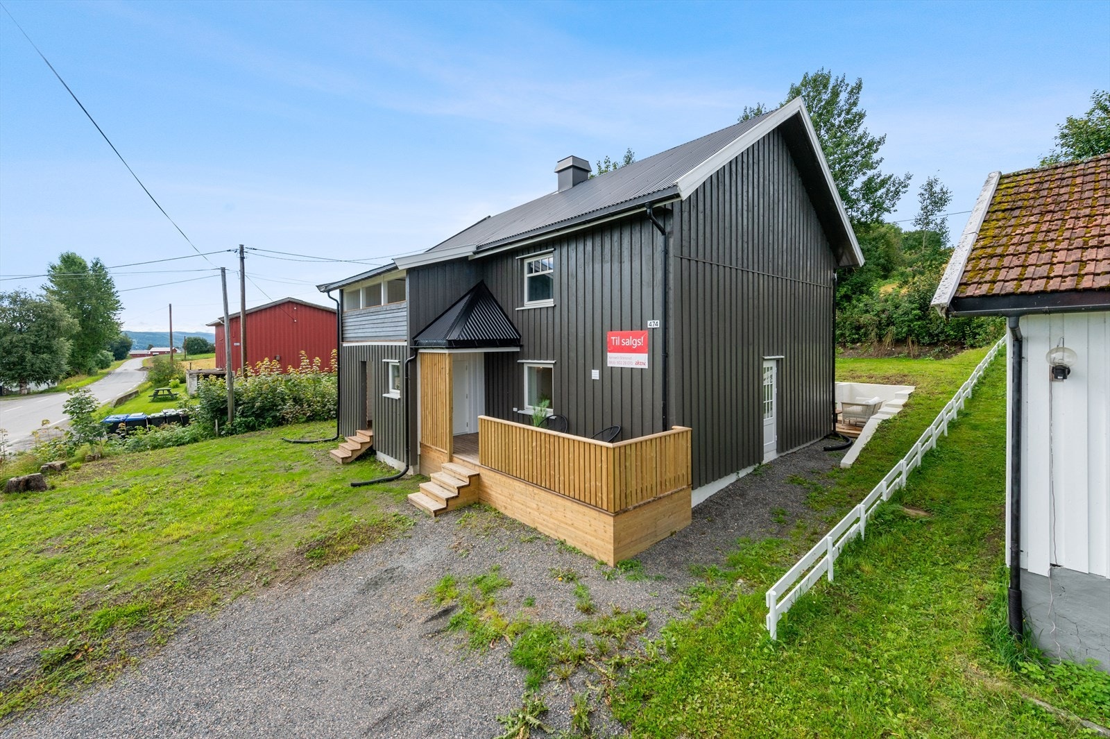 Slakt skrånende tomt med plen og gruset gårdsplass. Galleribilde