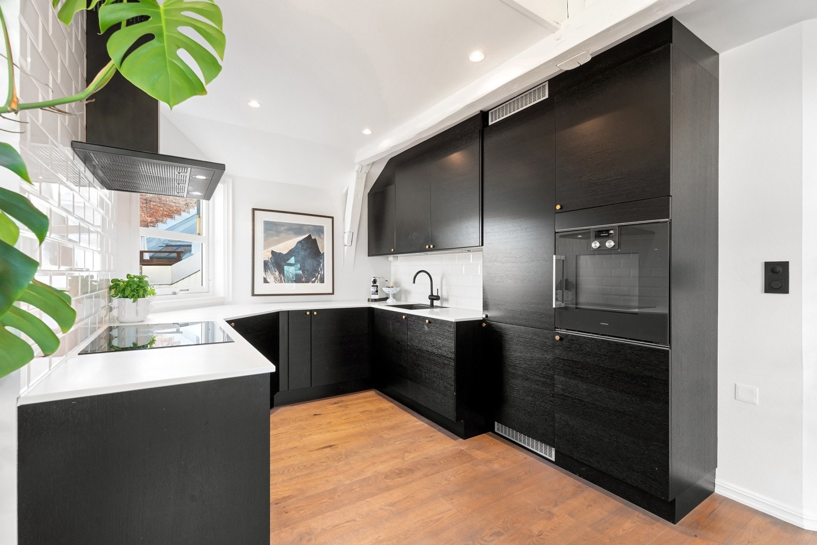 Innredningen har glatte, svarte fronter som gir et sofistikert preg, mens benkeplaten i steinkompositt med underlimt kum skaper et elegant helhetsinntrykk Galleribilde