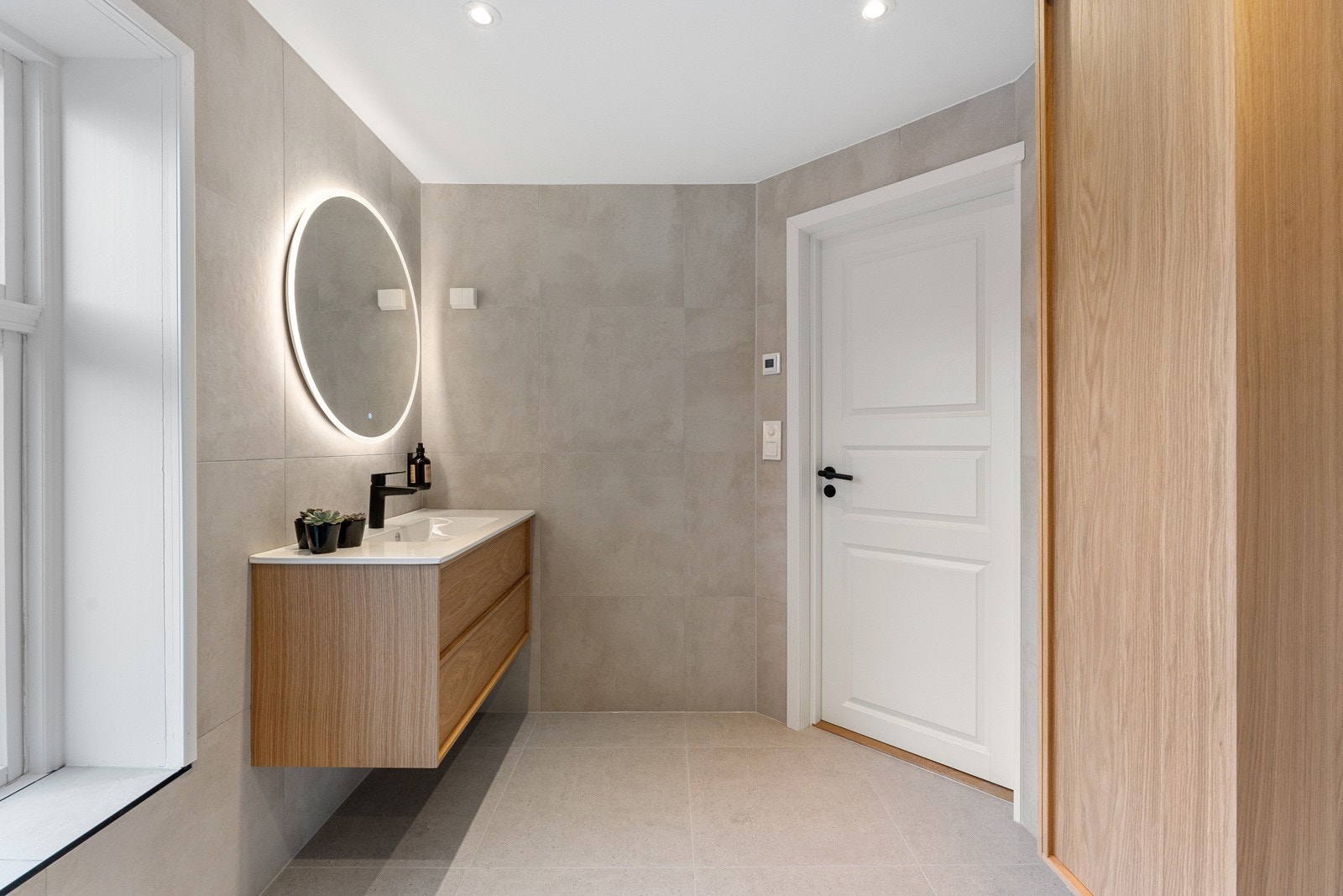 Badet er utstyrt med servant med underskap, vegghengt toalett og dusjhjørne med innfellbare glassdører. I tillegg er det varmekabler i gulv. Galleribilde