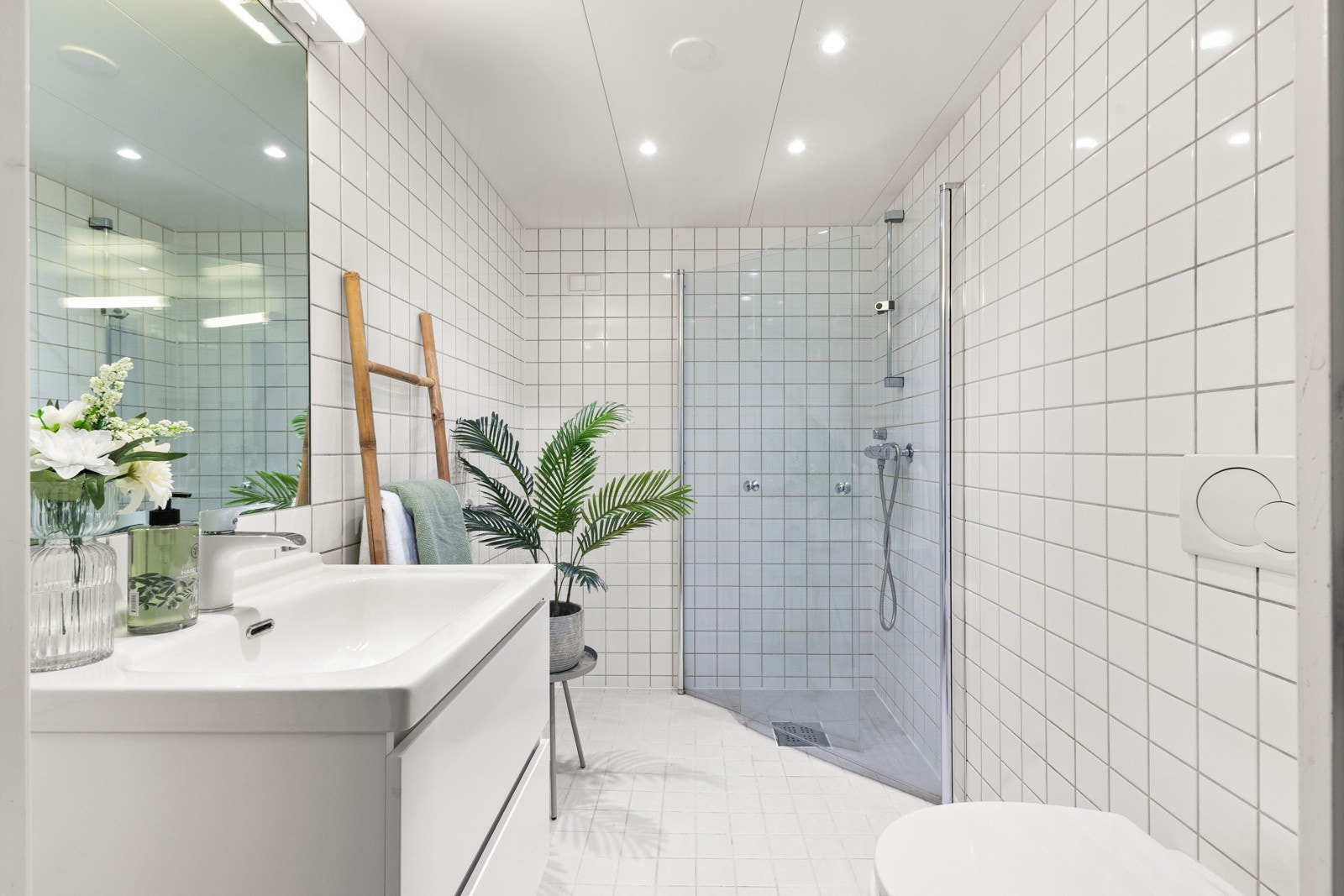 Pent og funksjonelt bad med flislagte vegger og lakkerte stålplater i himling med downlights Galleribilde