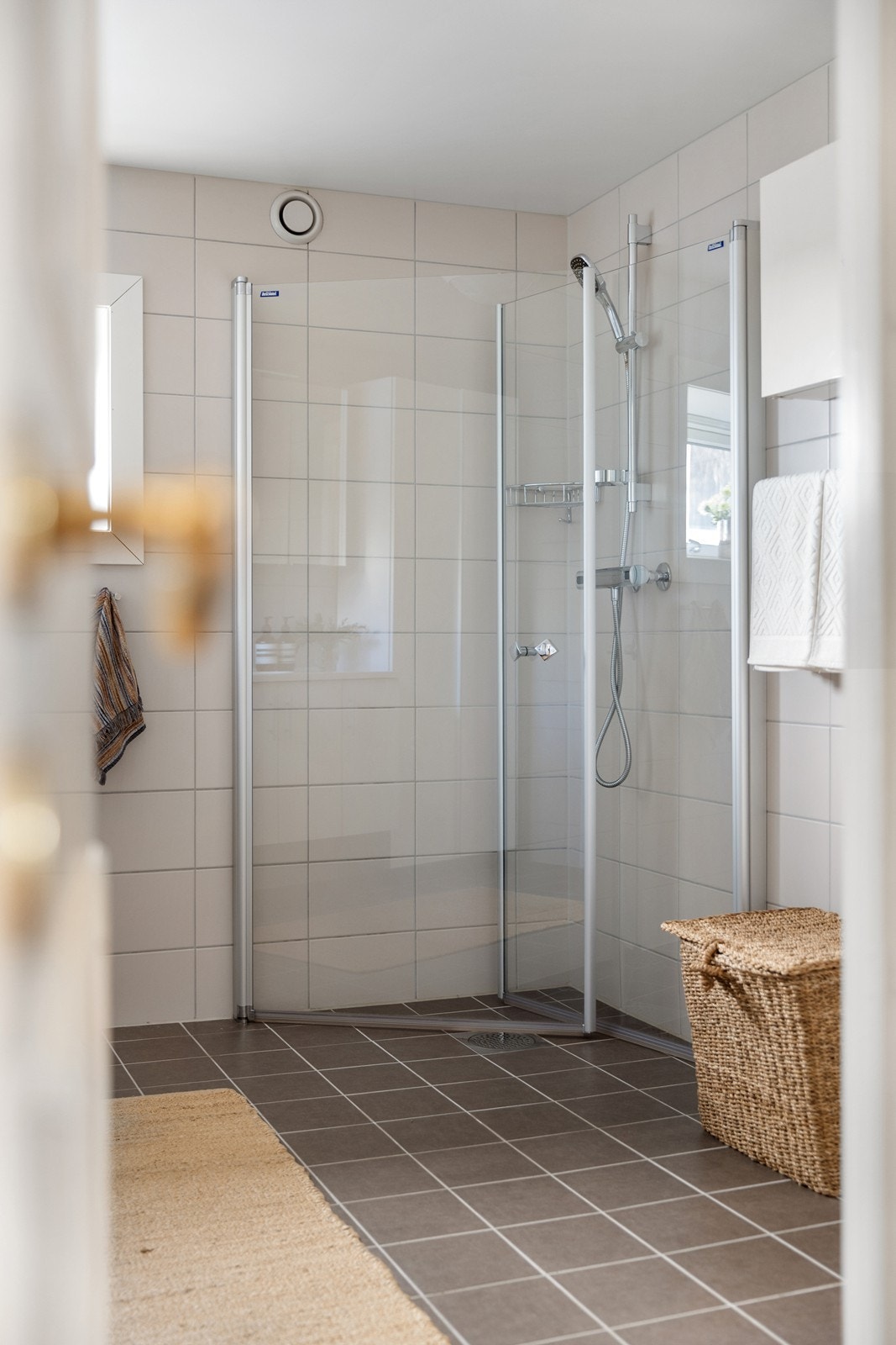 Det er varmekabler i gulvet. Badet inneholder en vegghengt servantinnredning med heldekkende vask og ett-greps armatur i krom, svingbare dusjvegger med termostatstyrt dusjbatteri og vegghengt toalett med innebygget sisterne. Galleribilde