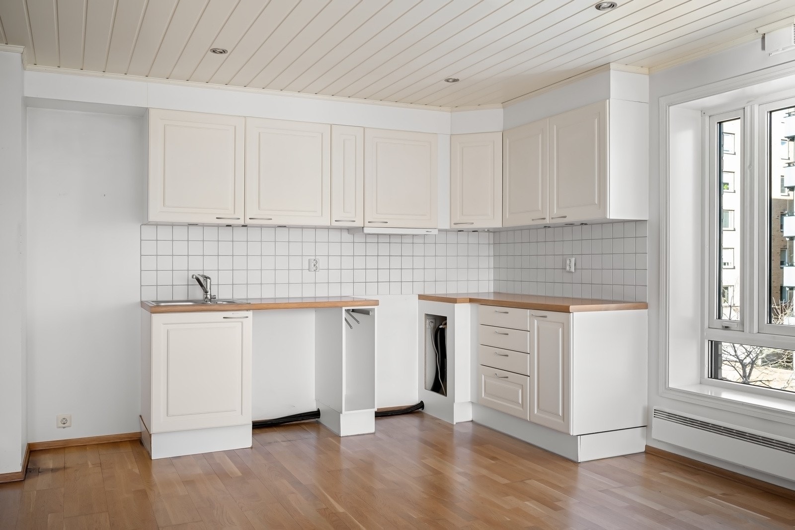 Kjøkkenet er i åpen løsning mot stuen og er utformet i en praktisk vinkelløsning, som gir godt med benke- og arbeidsplass. Innredningen består av kremhvite profilerte fronter med foring opp til tak og laminert benkeplate med nedfelt vaskekum. Galleribilde