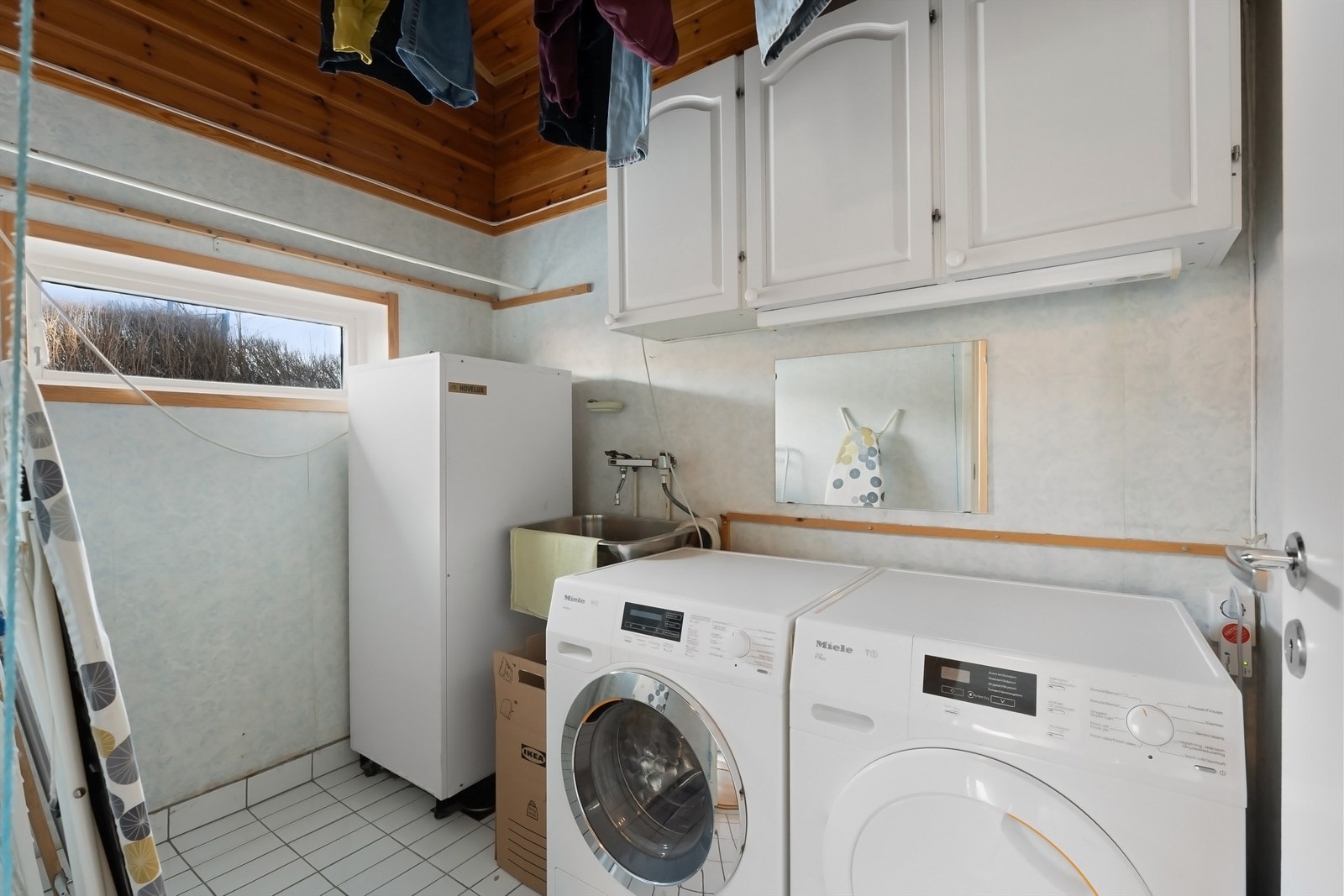 Praktisk vaskerom med skap, utslagsvask og opplegg for vaskemaskin og tørketrommel Galleribilde