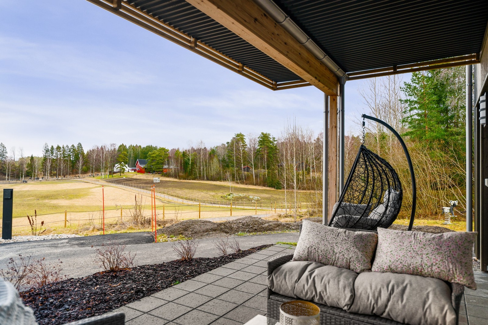 Hyggelig og landlig utsyn mot skogsområde og hestehold fra uteplassen. Galleribilde