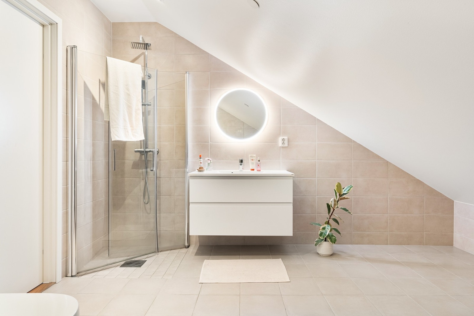 Det er helfliset med en slett malt i himling og har varmekabler i gulv. Badet er innredet med dusj med glassdører, vegghengt toalett, opplegg for vaskemaskin og baderomsinnredning. Galleribilde