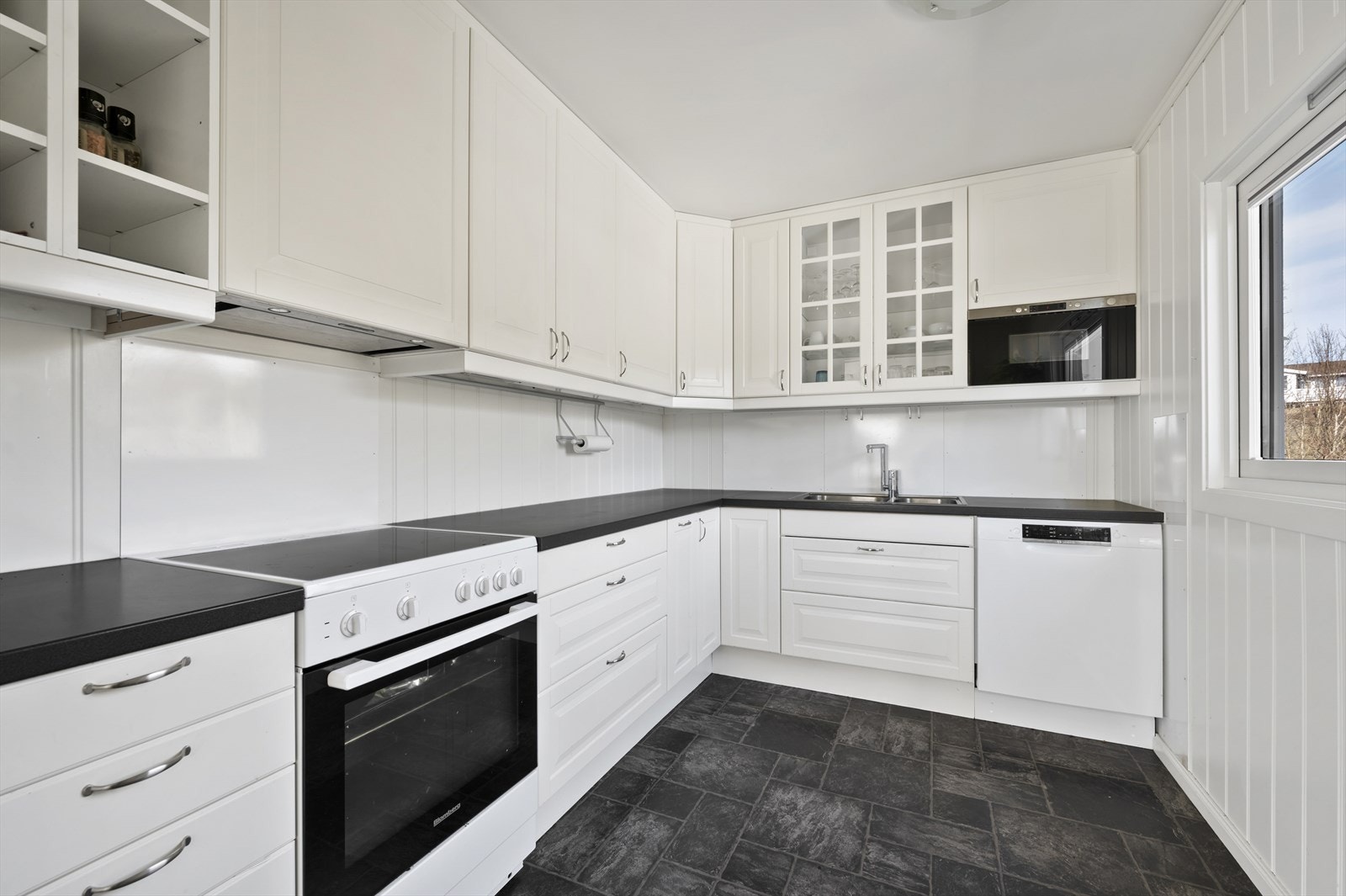 Tidløst kjøkken i hvit utførelse med mørke benkeplater. Galleribilde