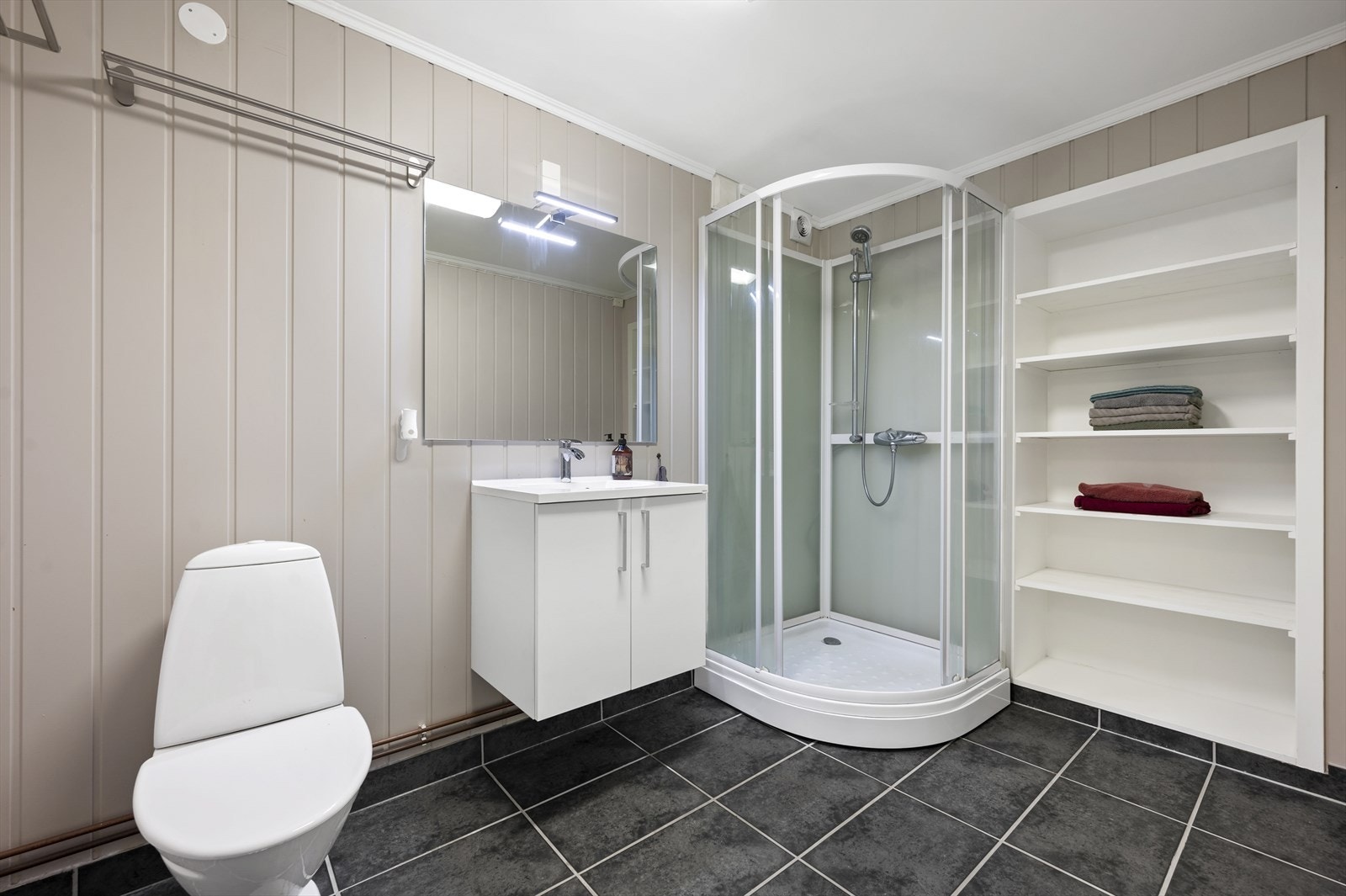 Bad med dusjkabinett, servant og god plass til oppbevaring. Galleribilde