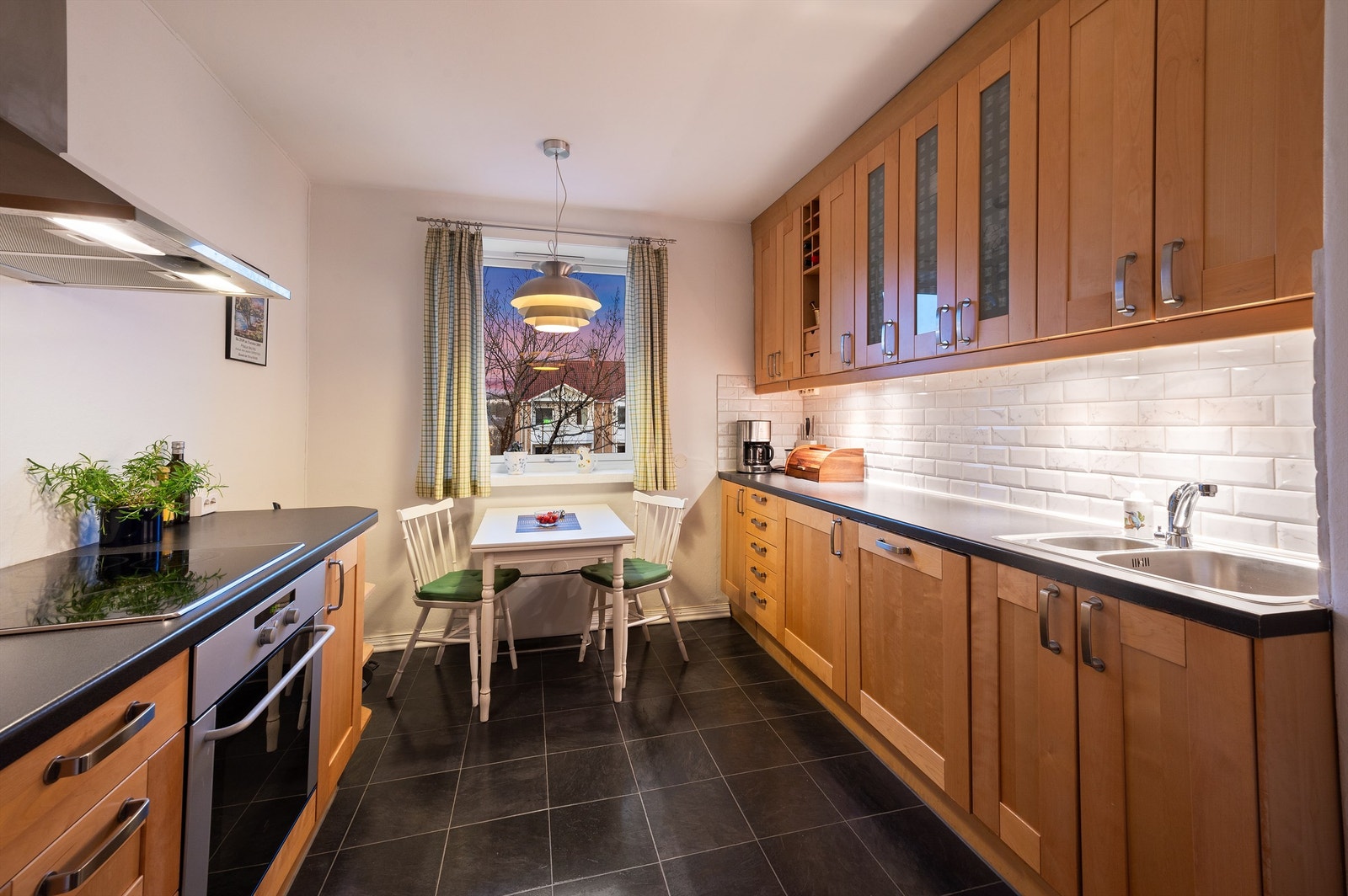 Over kjøkkenbenken er det pent flislagt med stikkontakter samt benkeskapsbelysning. Galleribilde