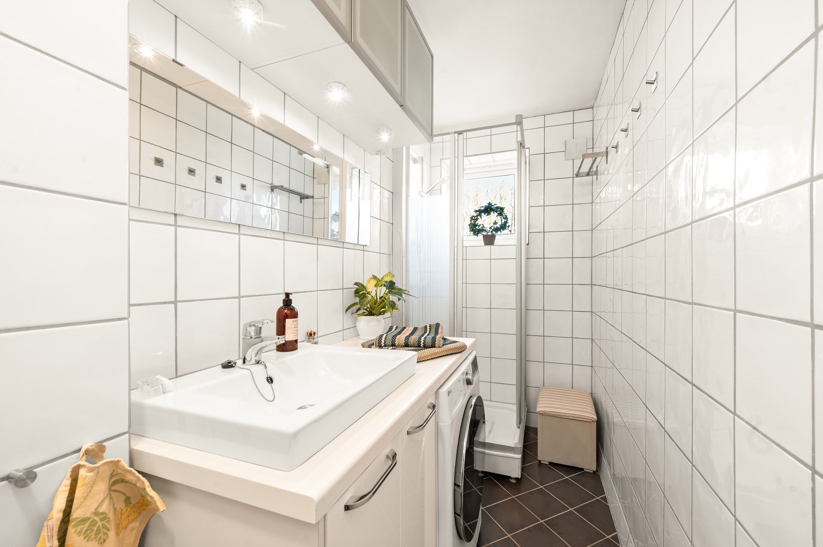 Badet er pent flislagt på gulv og vegger med varme i gulvet. Innredningen består av gulvstående servantskap med laminat benkeplate og nedfelt servant. Galleribilde