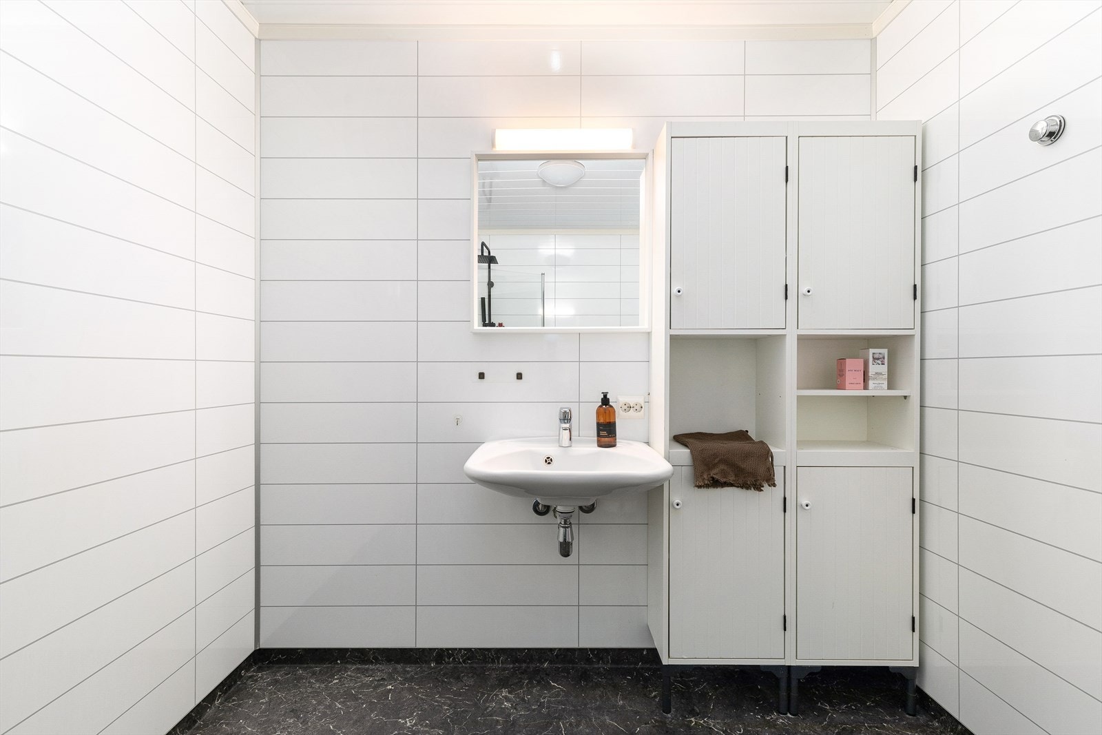 Badet er utstyrt med servant, spegel, wc og dusjhjørne. Galleribilde