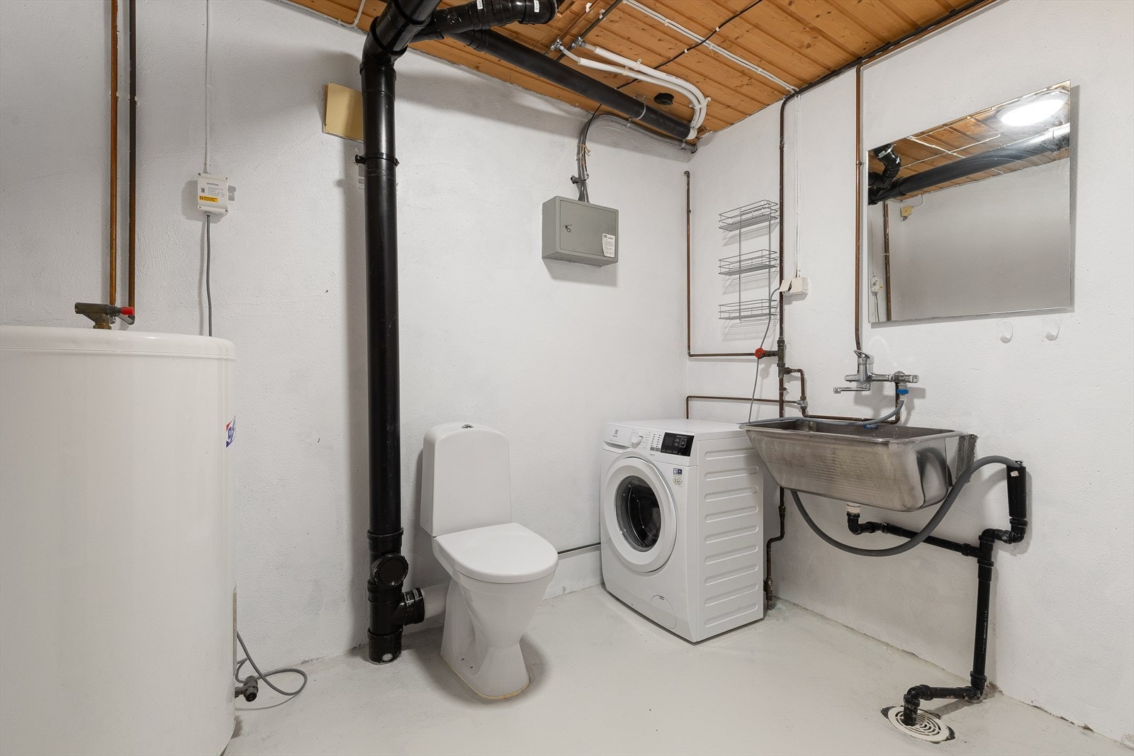 Vaskerom med pussa murveggar og betonggolv. Vaskerommet har wc og opplegg for vaskemaskin. Galleribilde