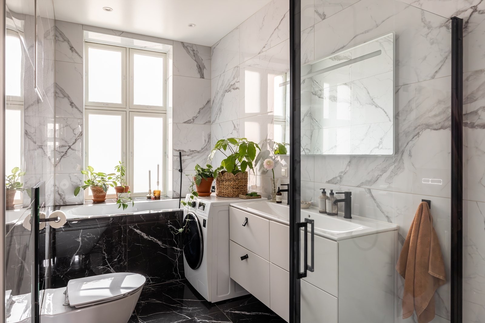 Meget lekkert bad med store fliser på vegger og gulv, som gir et eksklusivt uttrykk. Det er opplegg for vaskemaskin. Galleribilde