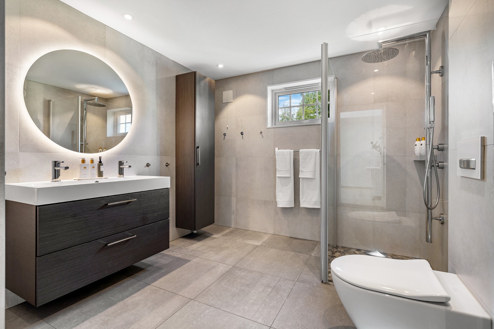 Pent flislagt bad med moderne baderomsinnredning, samt godt med oppbevaringsmuligheter. Det er varme i gulv. Galleribilde