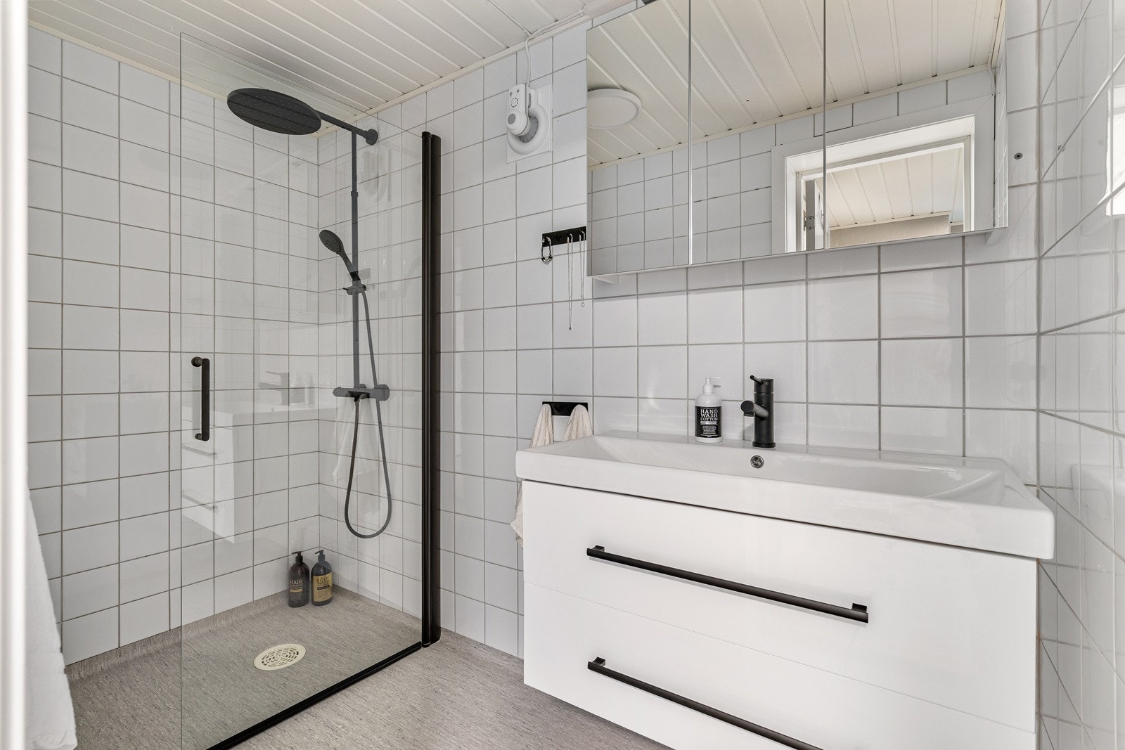 Flislagt baderom i underetasjen med moderne innredning og regndusj i dusjnisje. Galleribilde