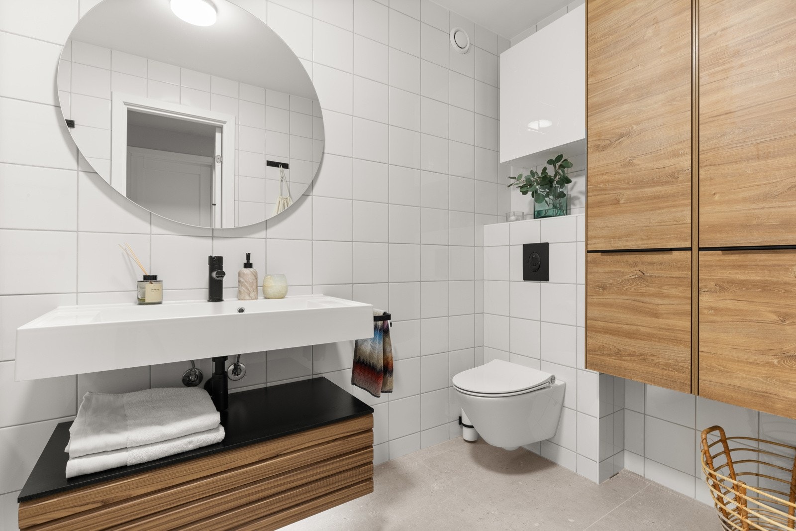 Badet er utstyrt med servantinnredning med helstøpt servant, speil med lys, vegghengt toalett, vegghengte skap og badekar med dusjarmatur. Galleribilde