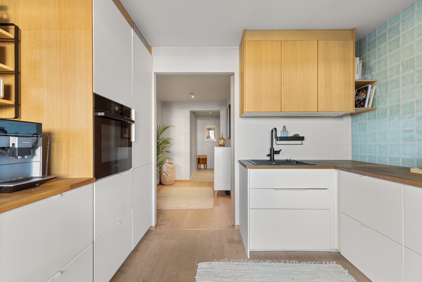 Kjøkkenet fremstår som moderne og tidsriktig med kombinerte overflater i hvit og lys eik. Galleribilde