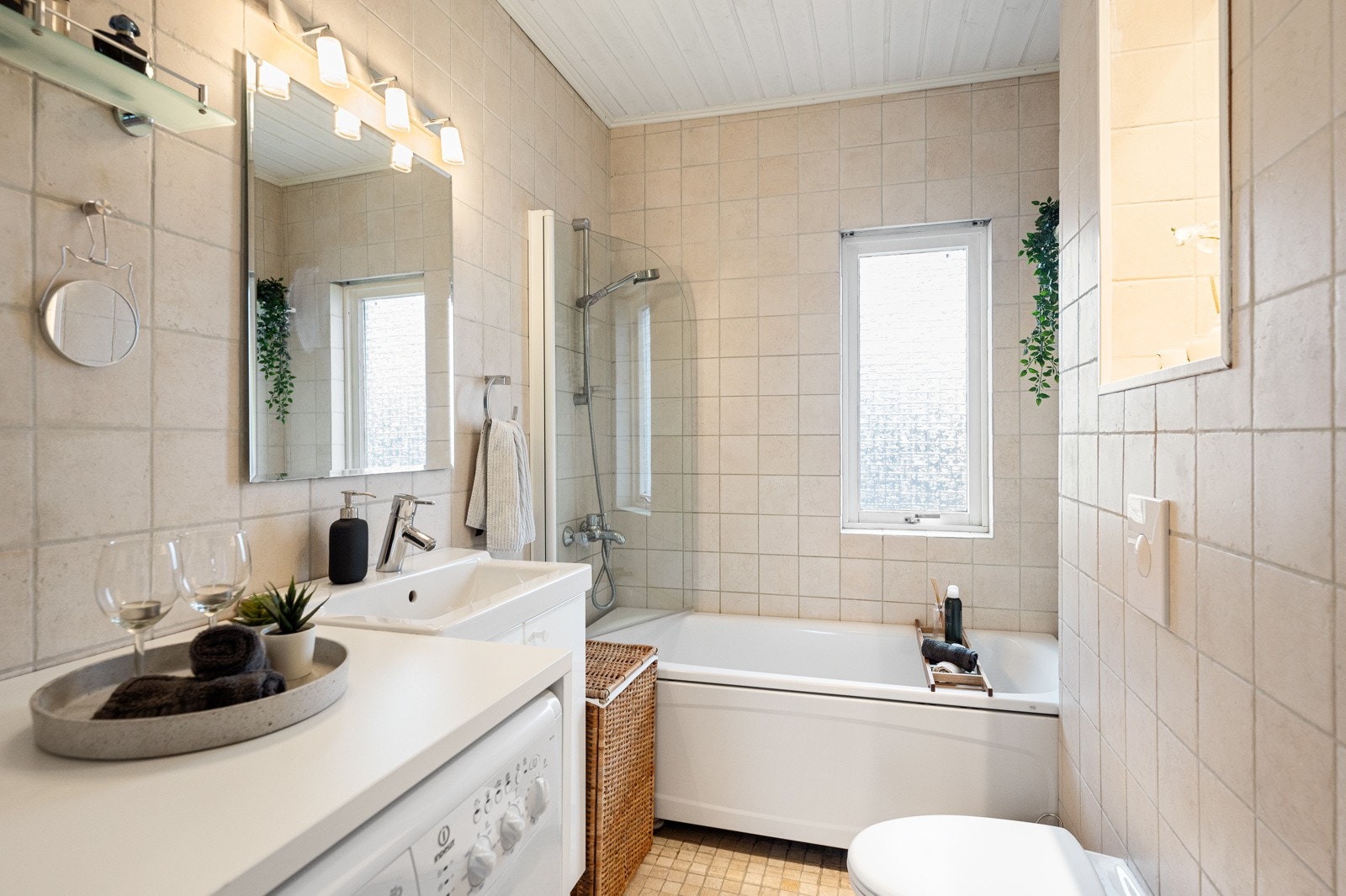 Badet er innredet med vegghengt klosett, badekar med dusj, opplegg for vaskemaskin, servant med skap og speil over. Galleribilde