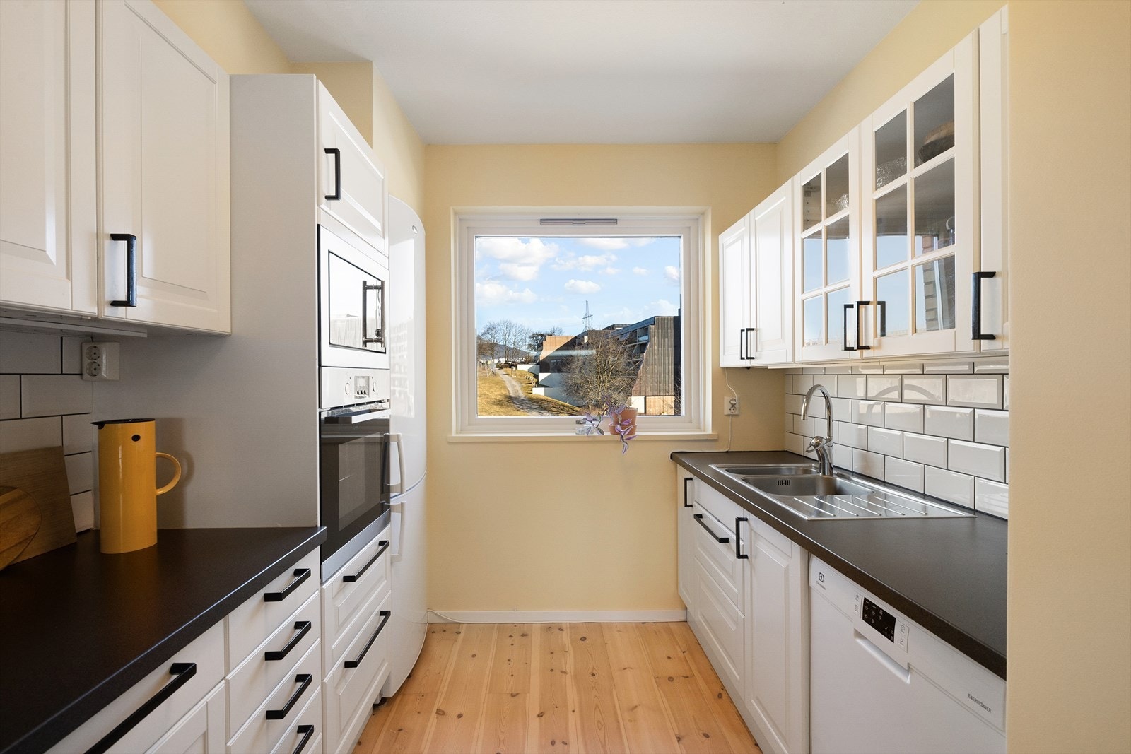 Kjøkkenet er utstyrt med hvitevarer som komfyr, platetopp, oppvaskmaskin, mikro og frittstående kjøl/ fryseskap. Det er kjøkkenventilator med antatt avtrekk ut til yttervegg. Galleribilde